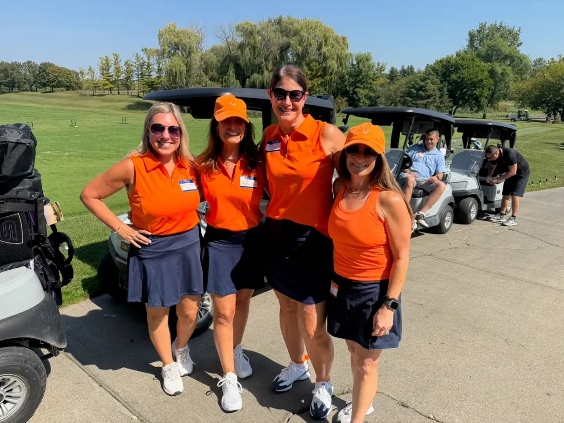 Event staff in orange shirts lined up by golf carts