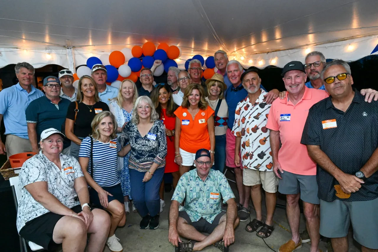 Large group of alumni gathered inside the event tent