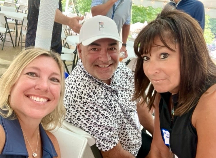 Three people smiling at outdoor event