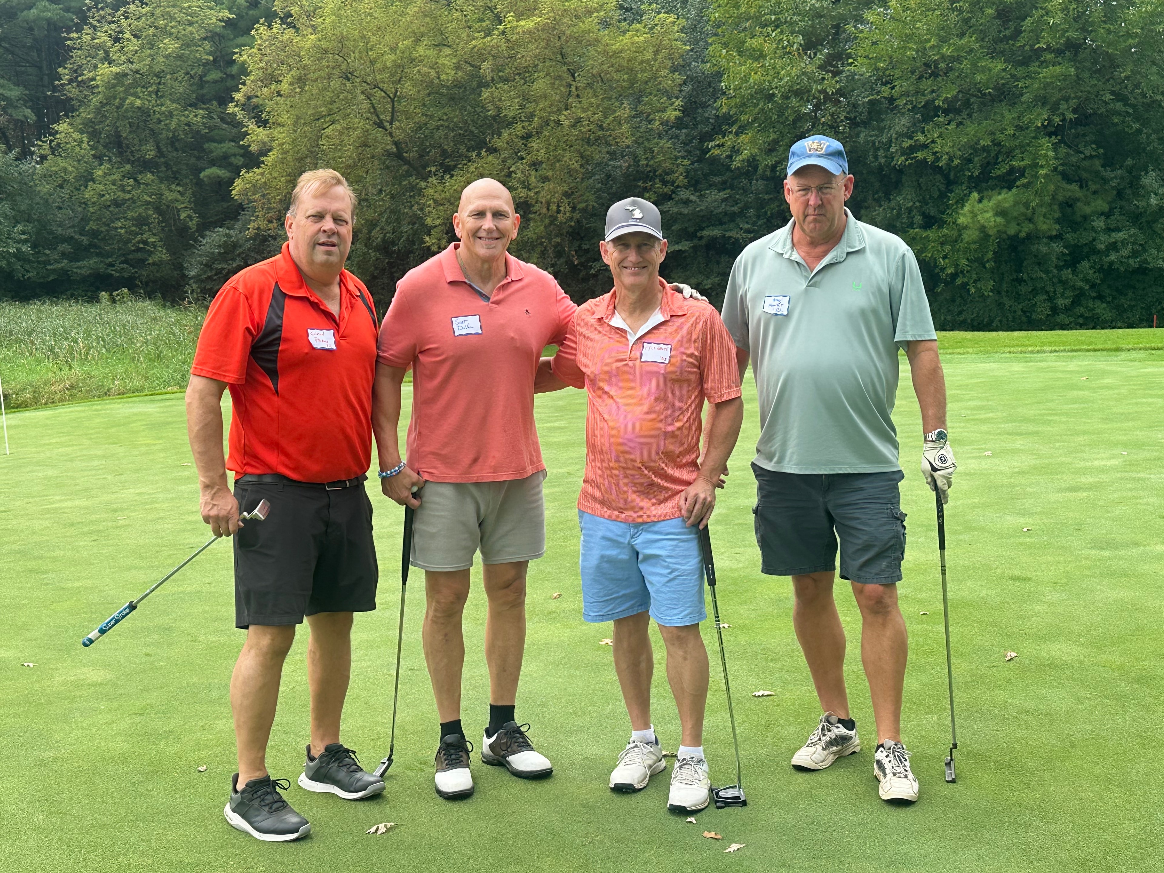 Four men golfing on green fairway