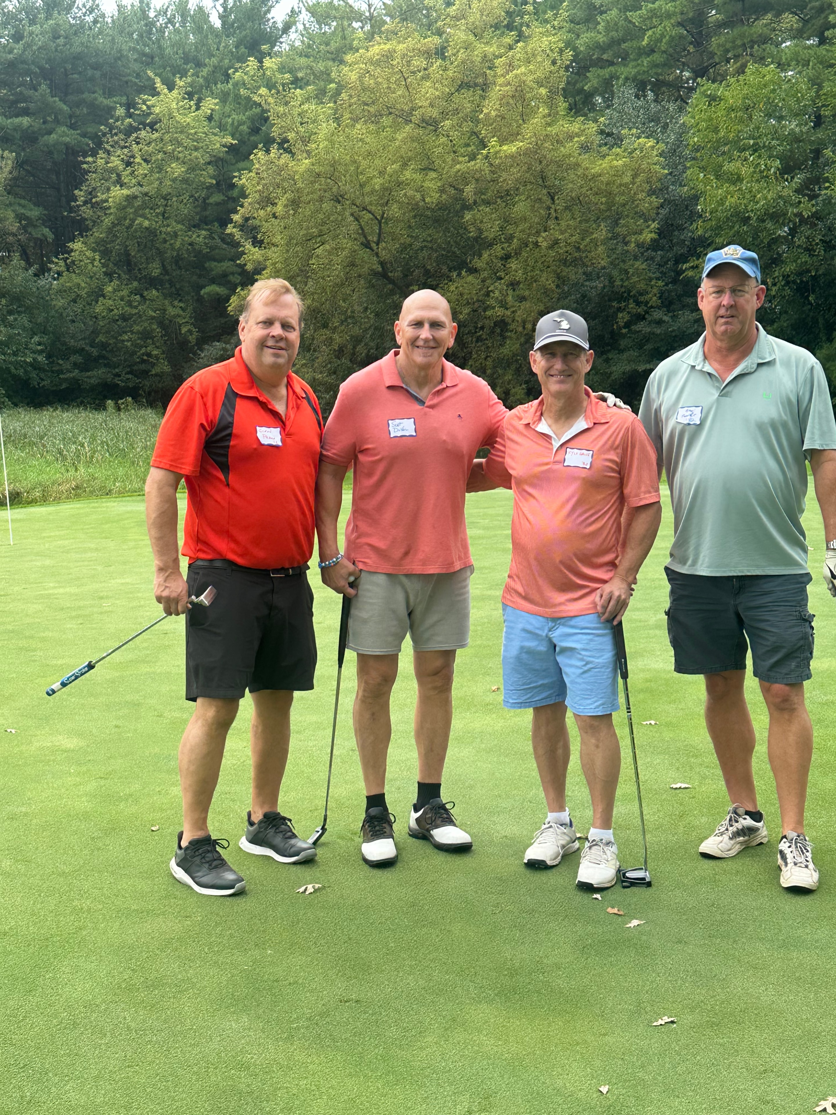 Four men golfing on green course