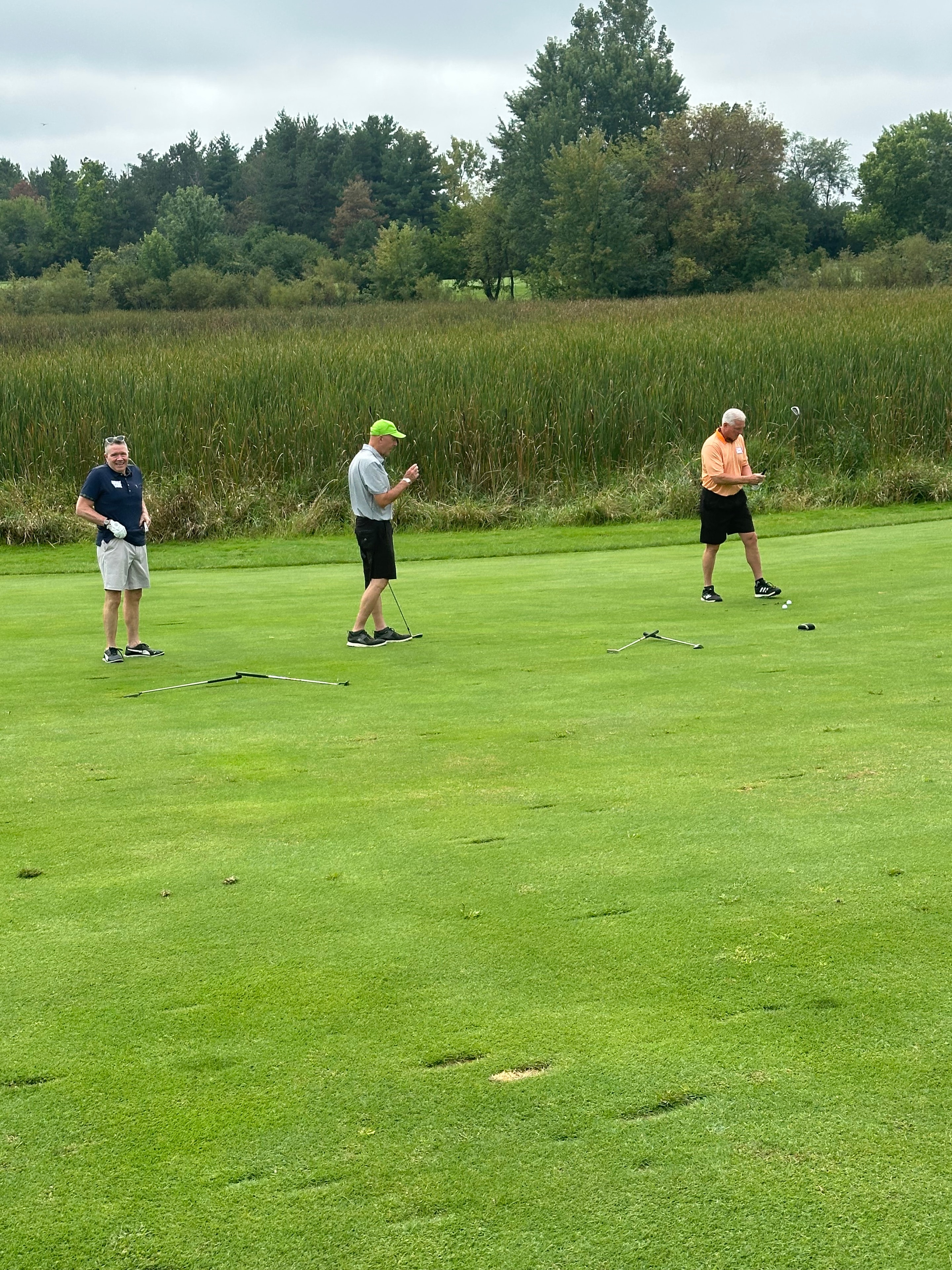 Three men playing cornhole on grass