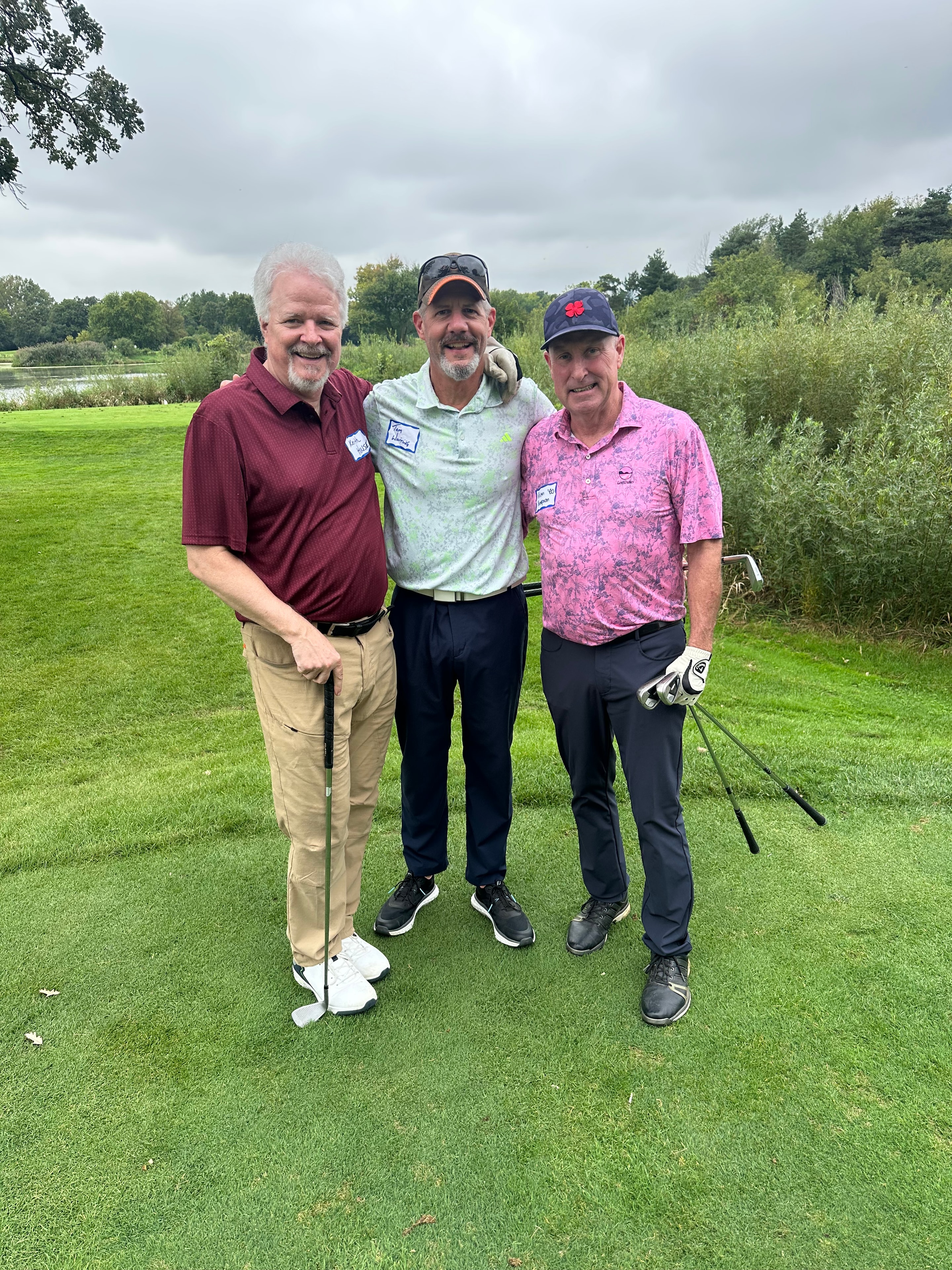 Three men posing on golf course lakeside
