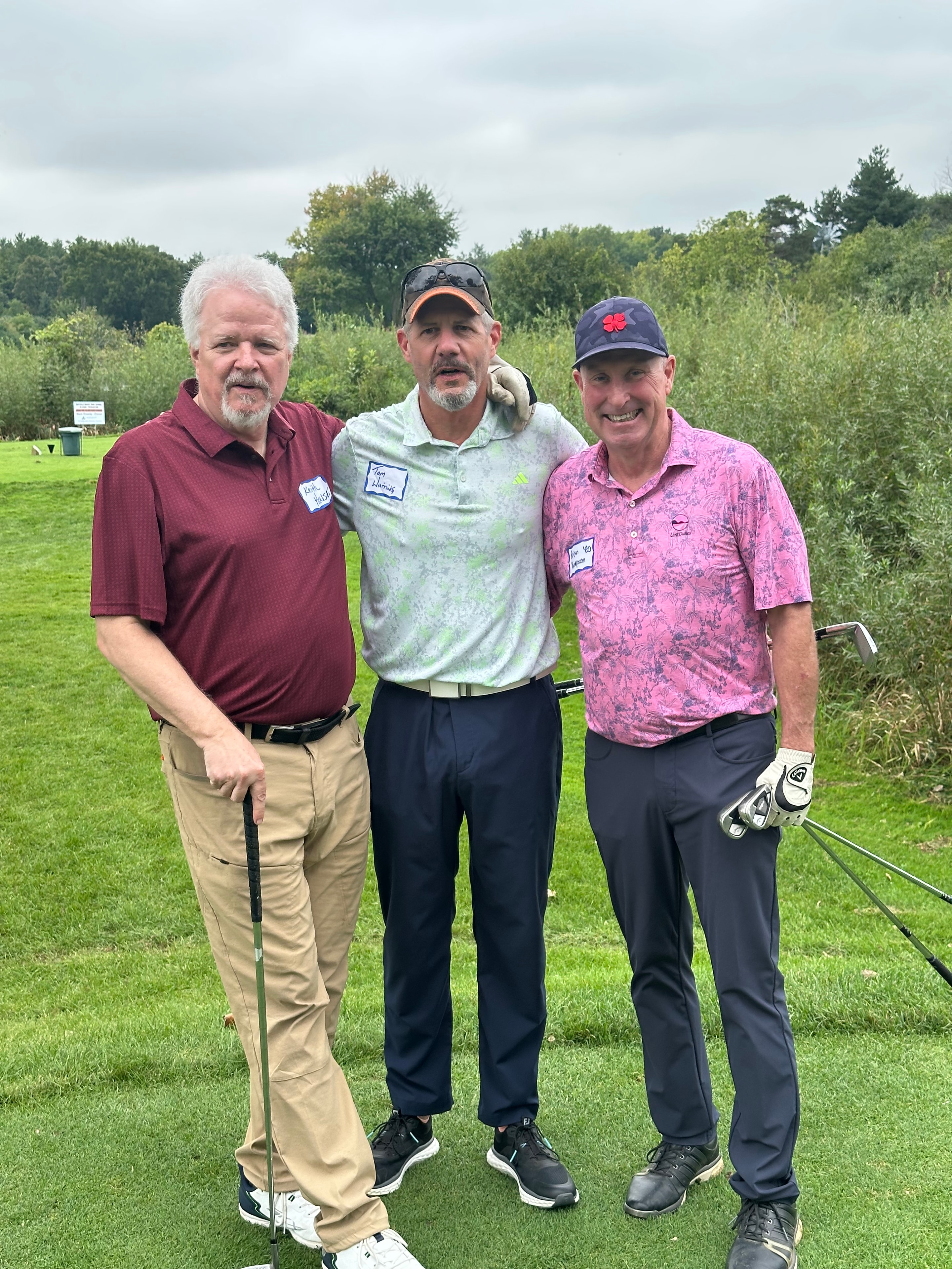 Three men posing on golf course