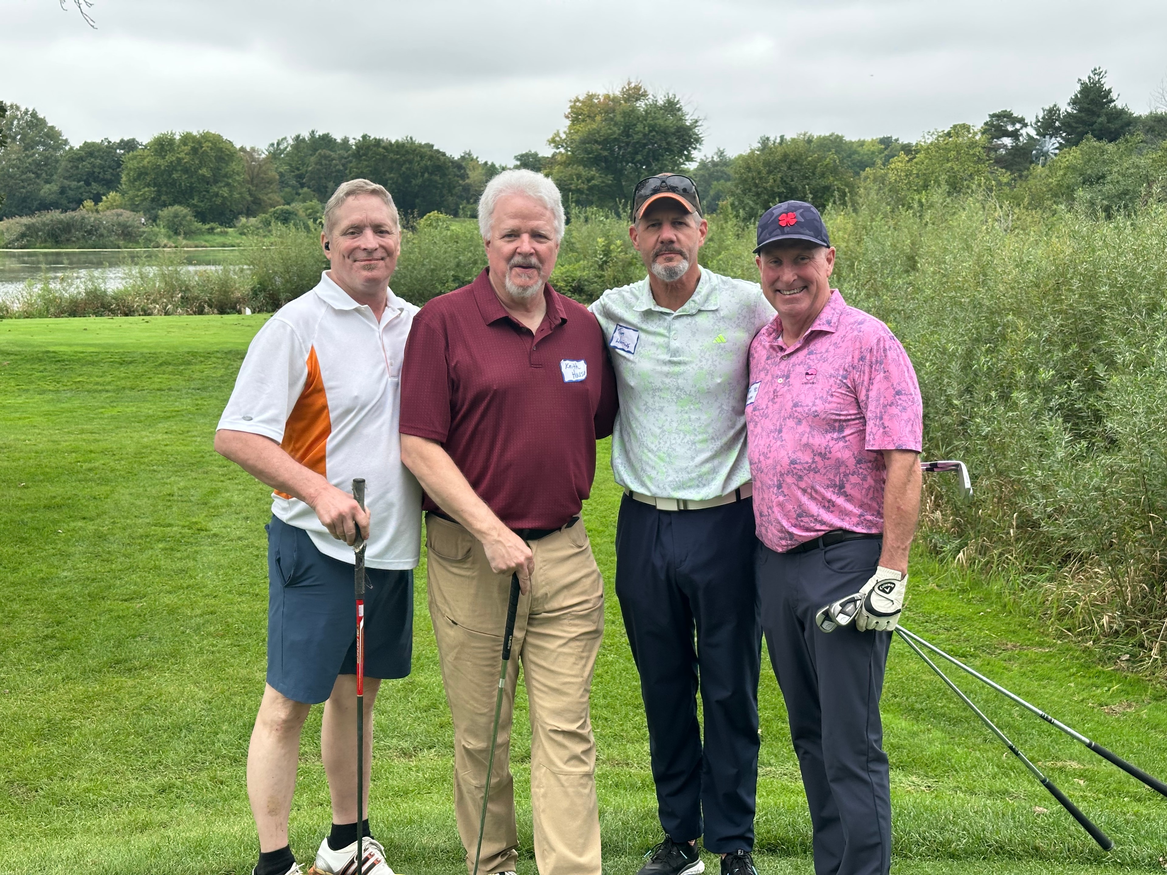 Four men posing on golf course riverside