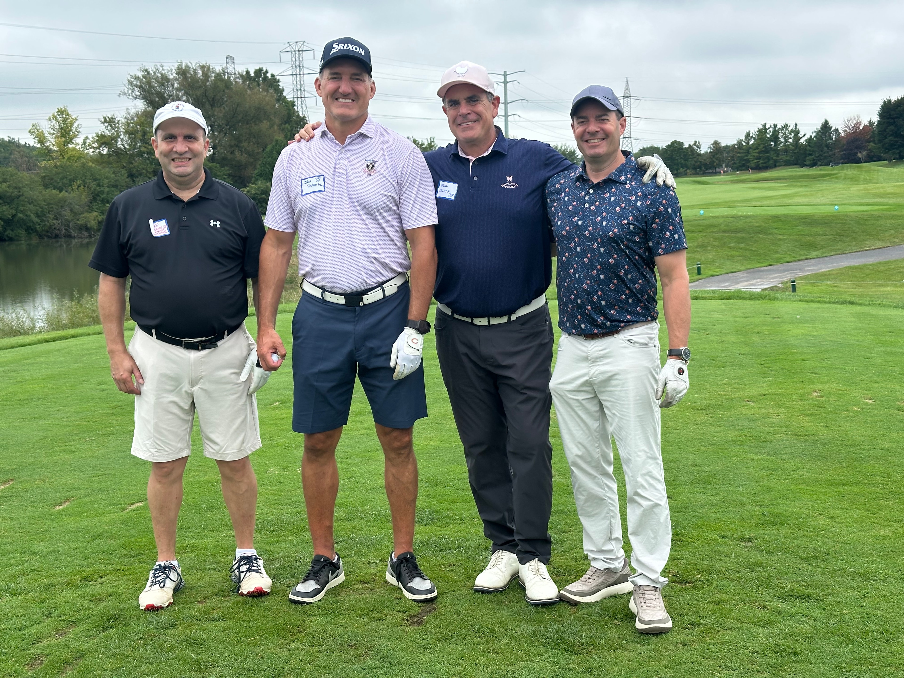 Four men posing on golf course fairway