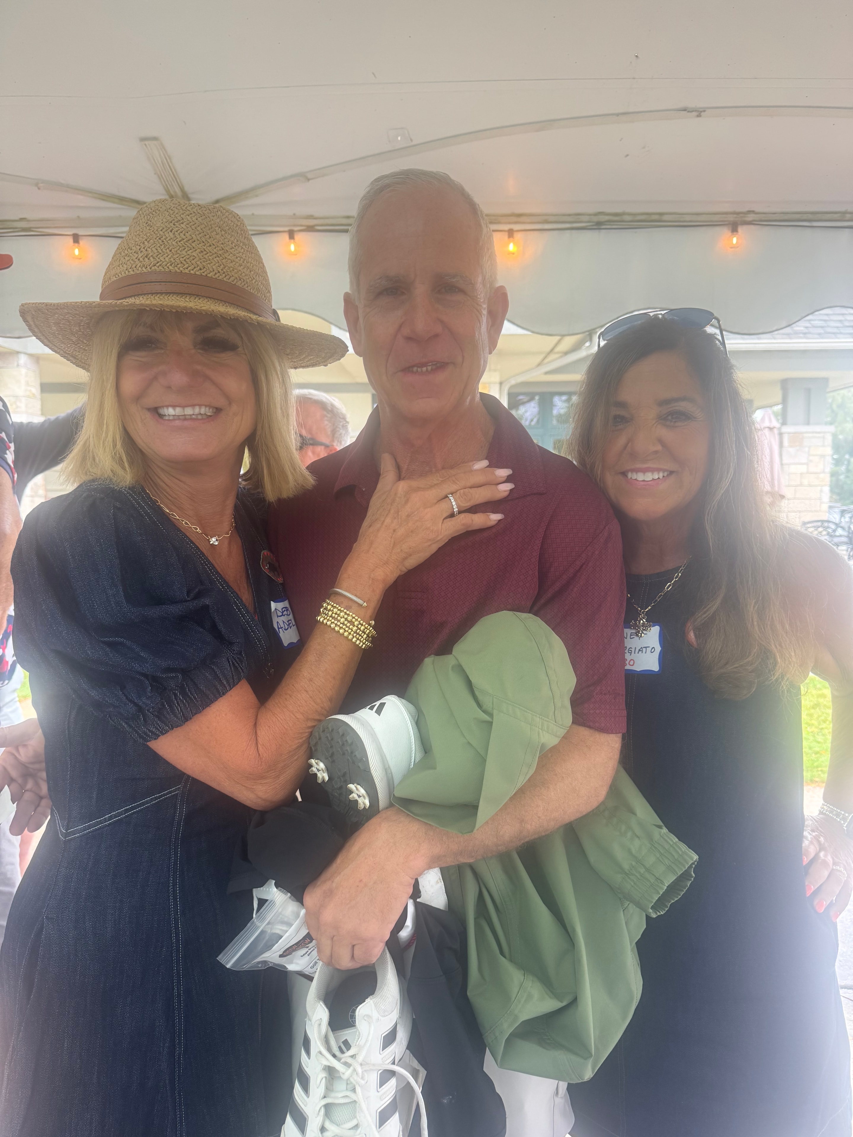 Three people smiling at outdoor event tent