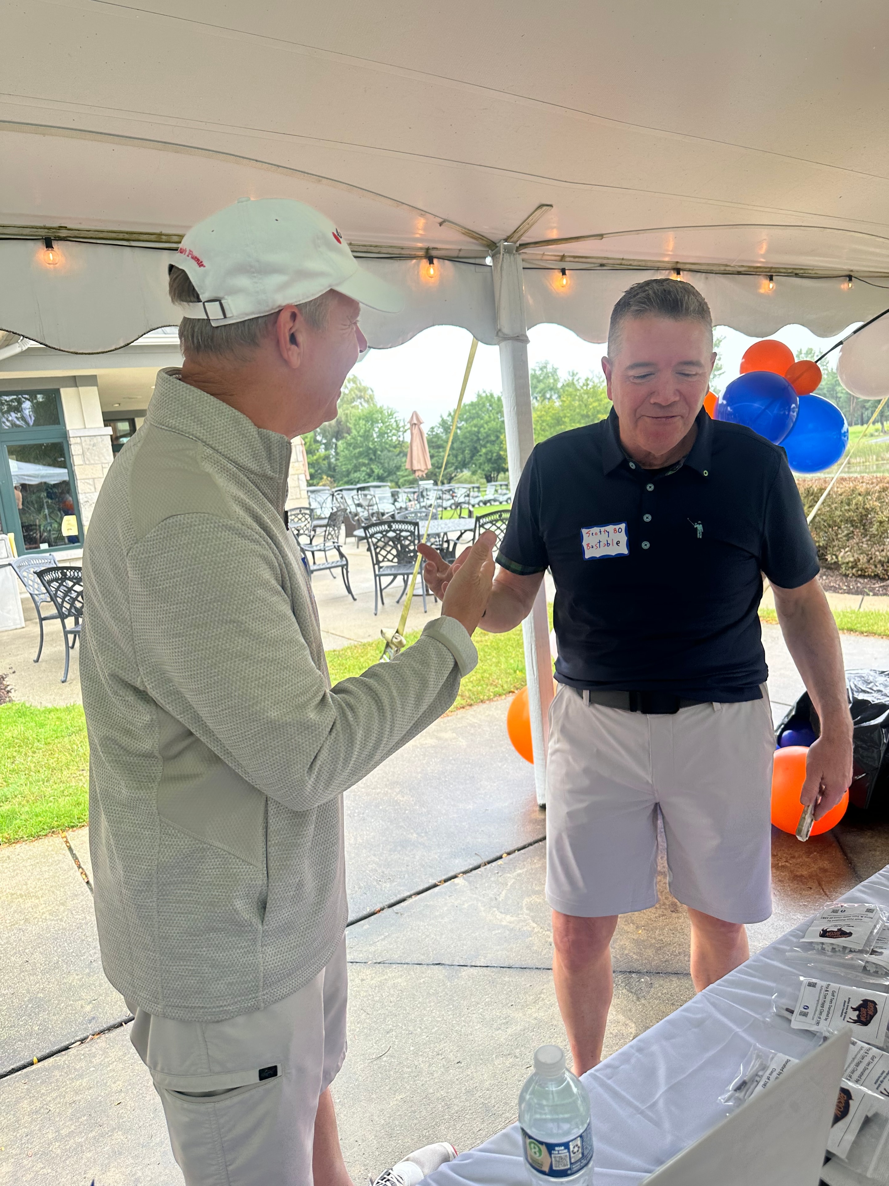 Two men conversing under outdoor event tent