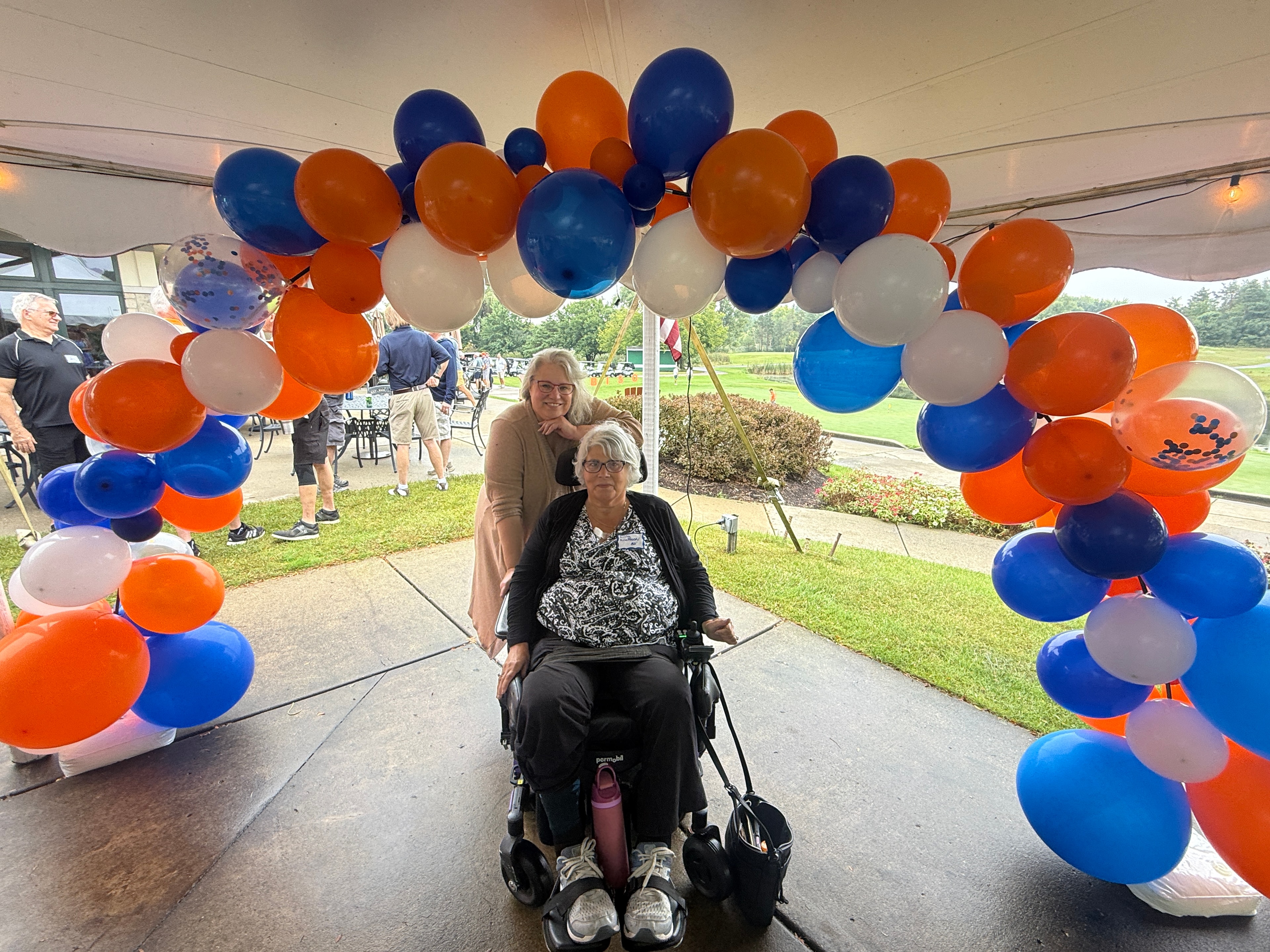 Two women posing under balloon arch
