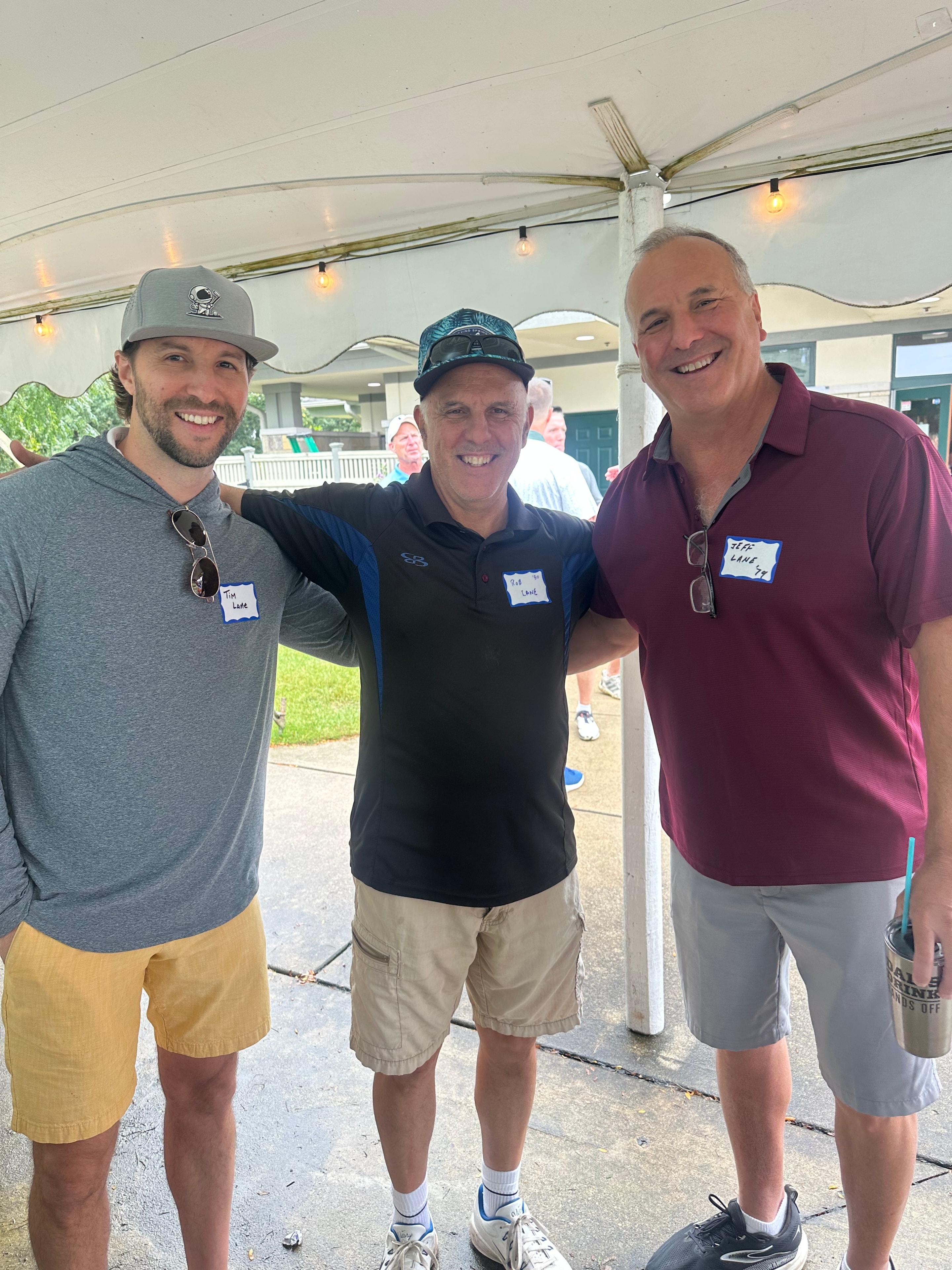 Three men posing together under tent