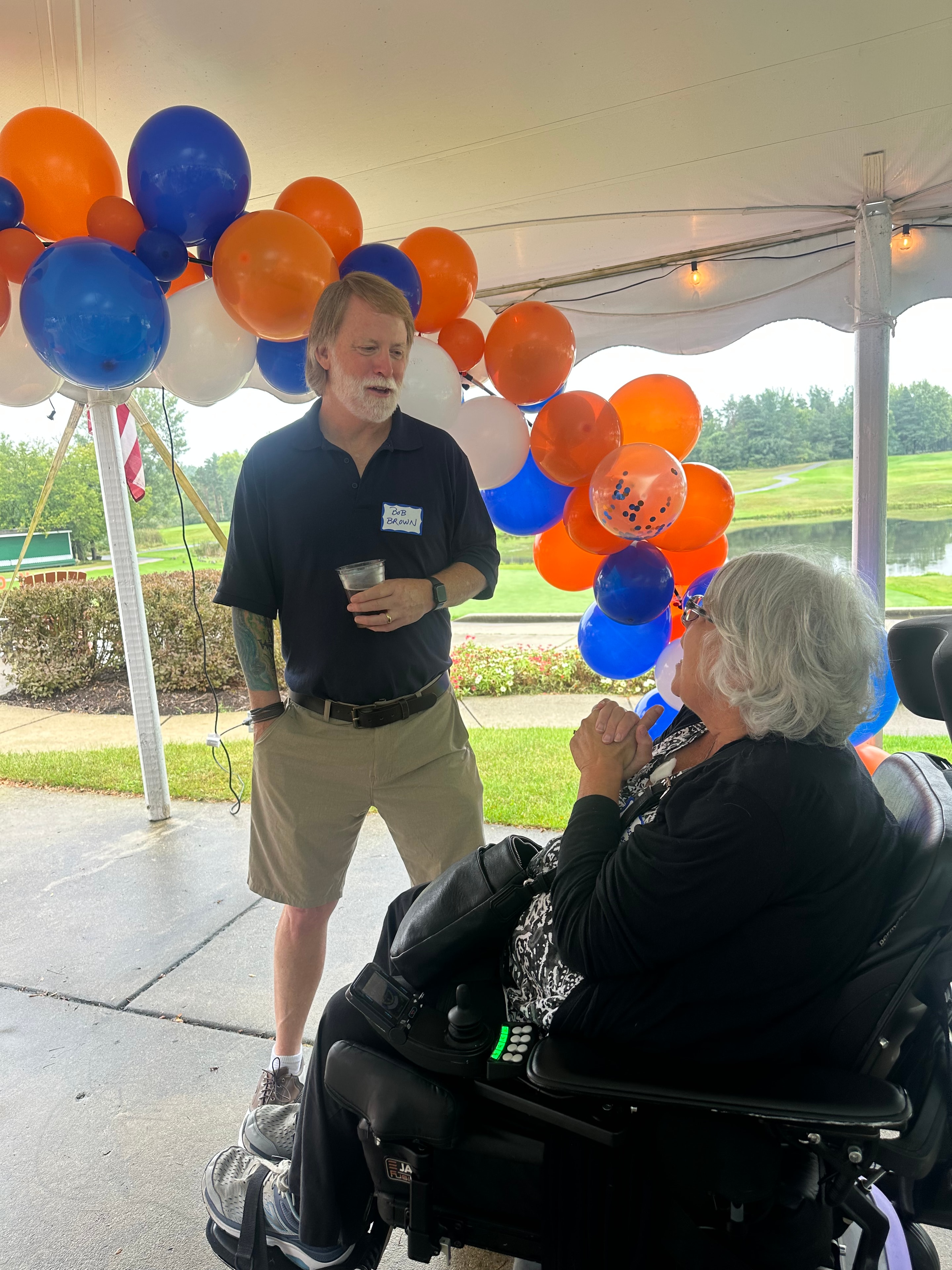 Man speaking to woman in wheelchair under balloons