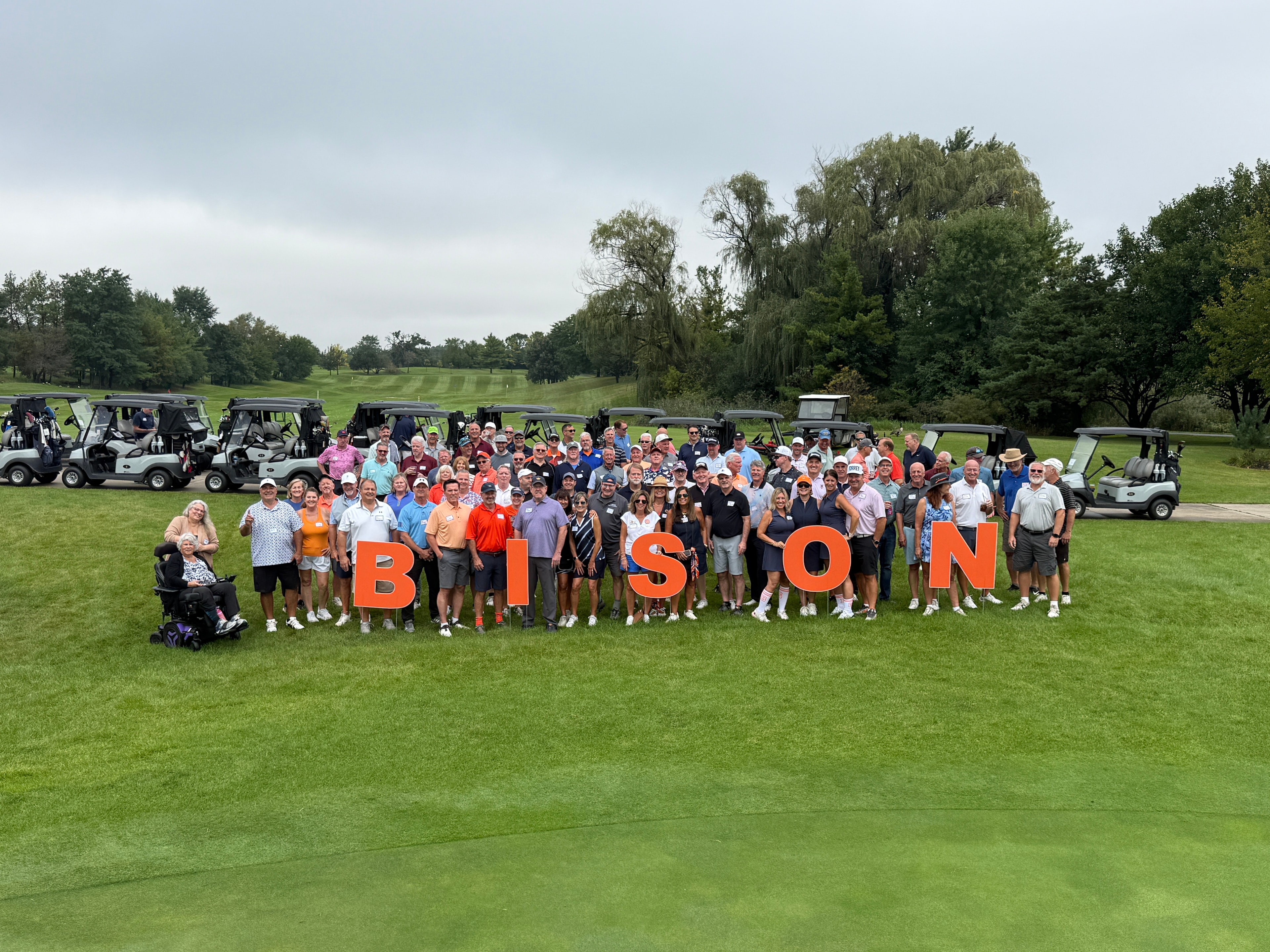 Large group posing with Bison letters on golf course