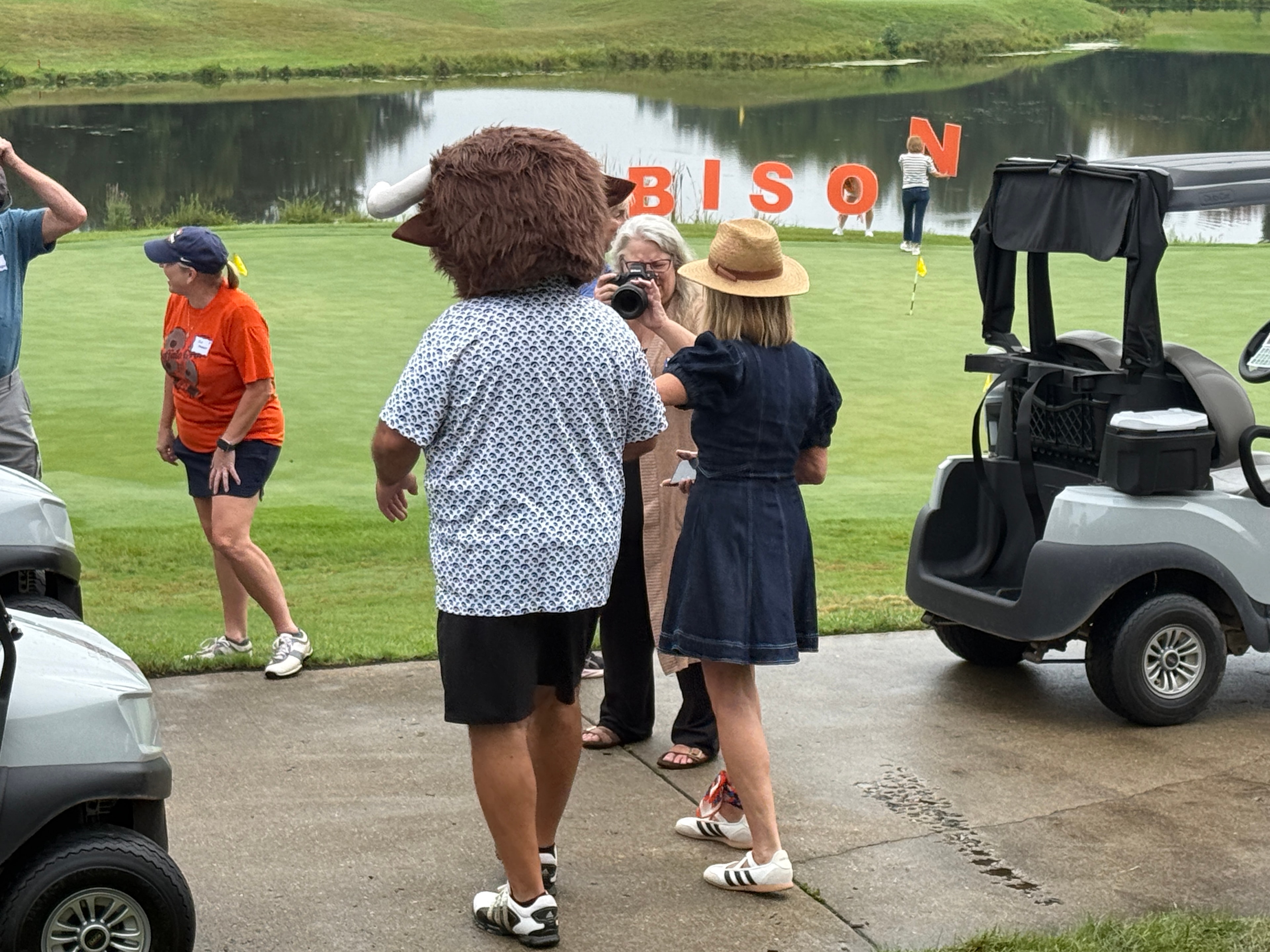 Bison mascot posing with people at golf event