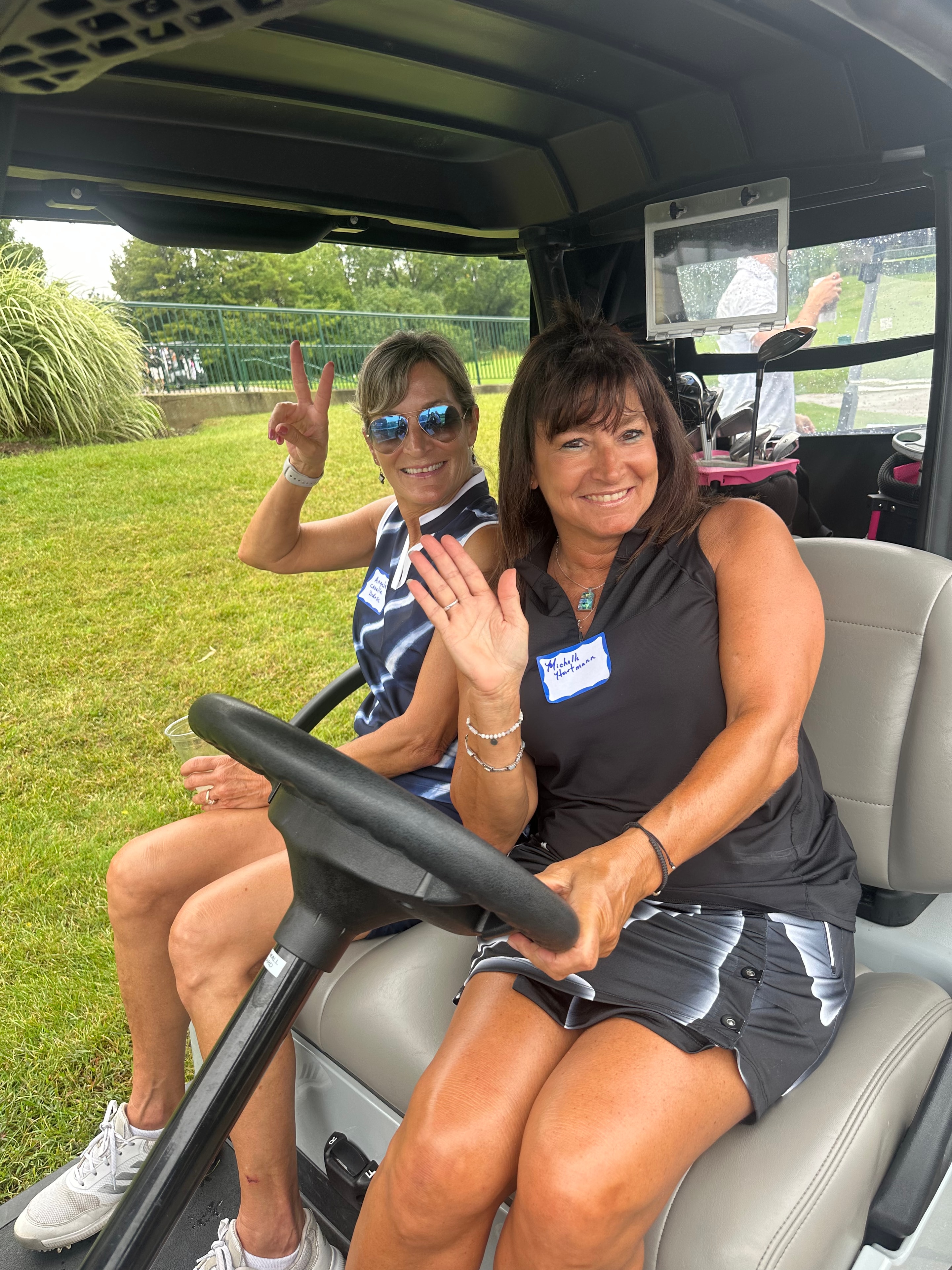 Two women waving in golf cart