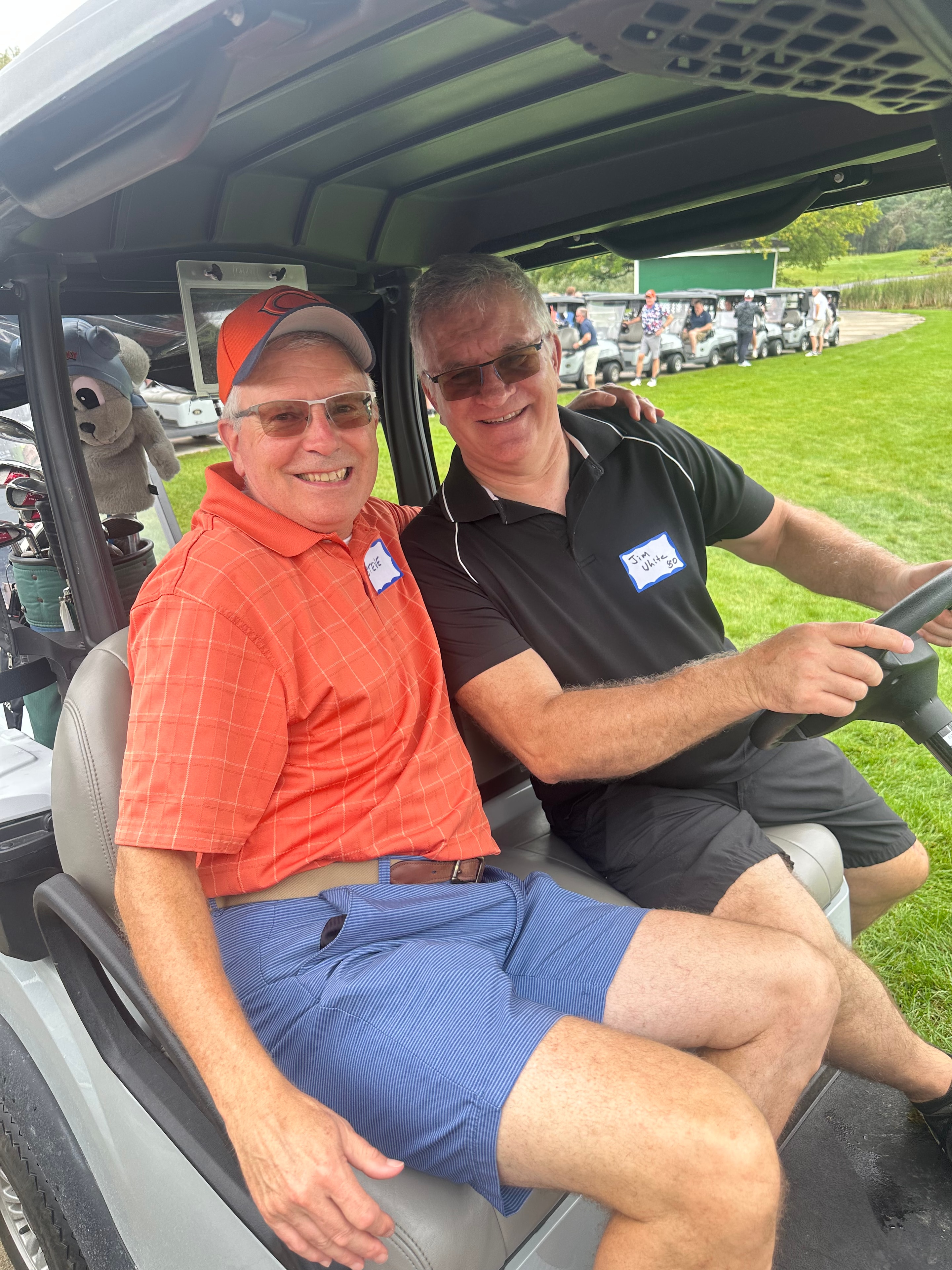 Two men smiling in golf cart