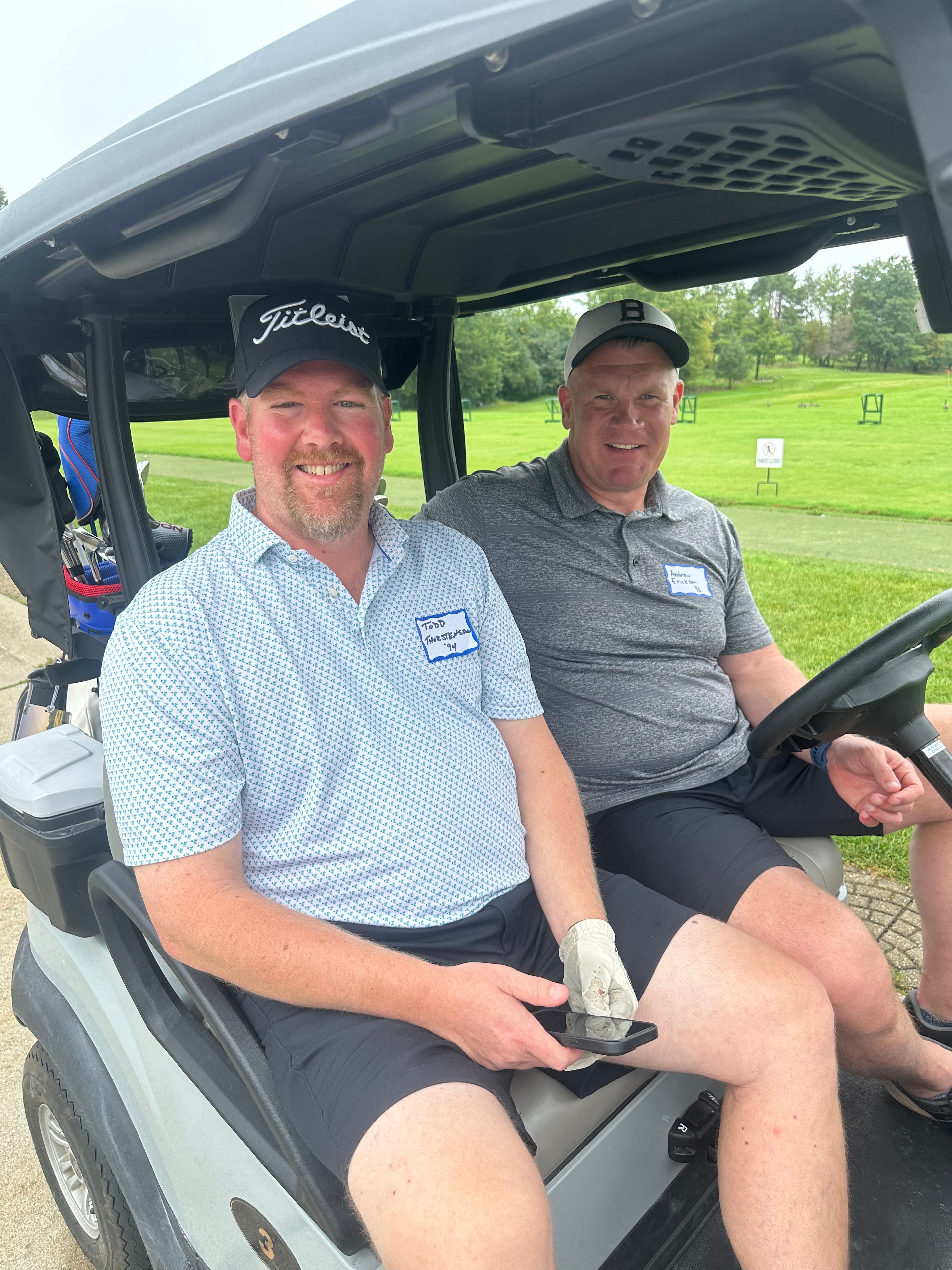 Two men in golf cart at course