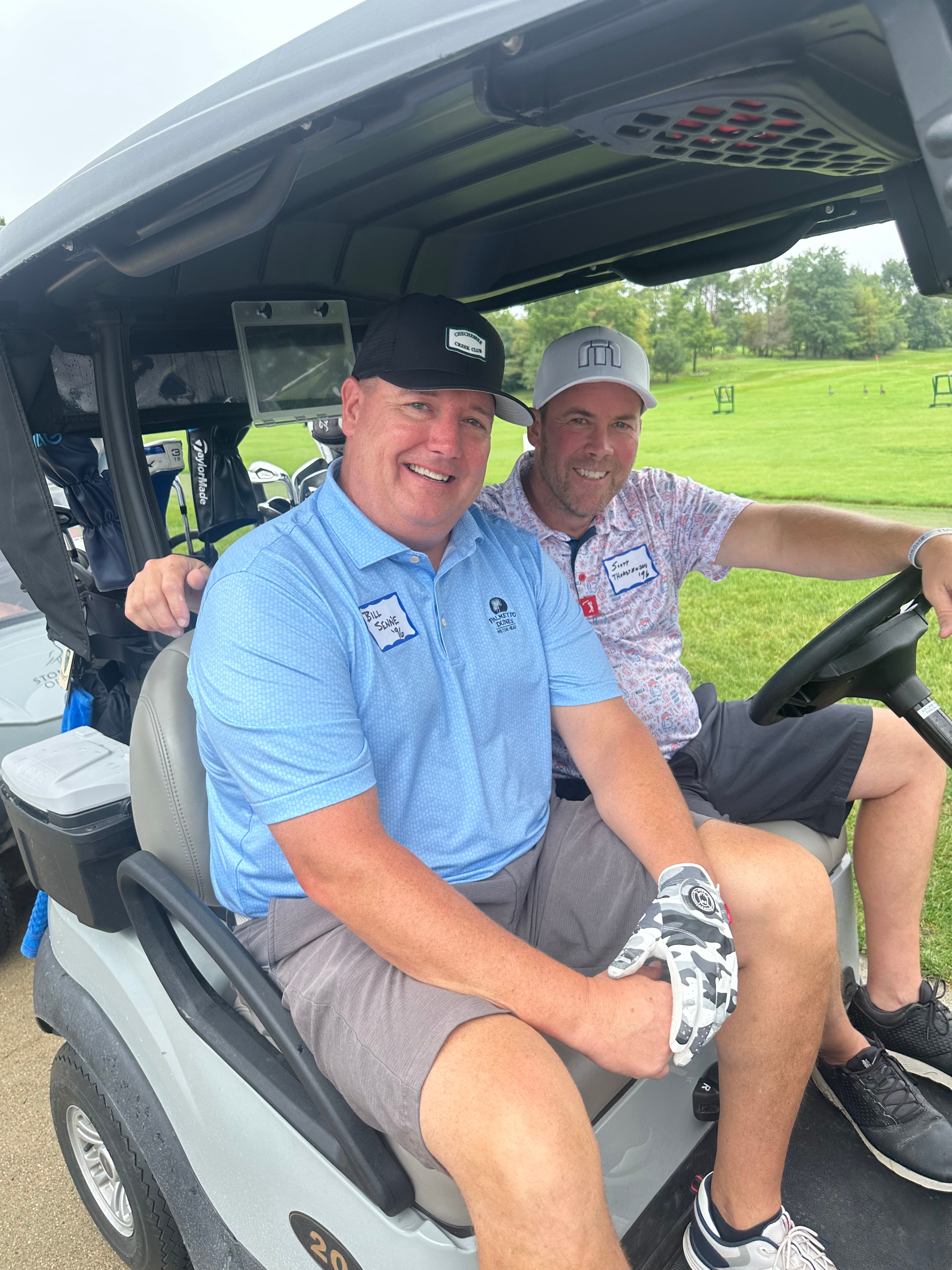 Two men smiling in golf cart