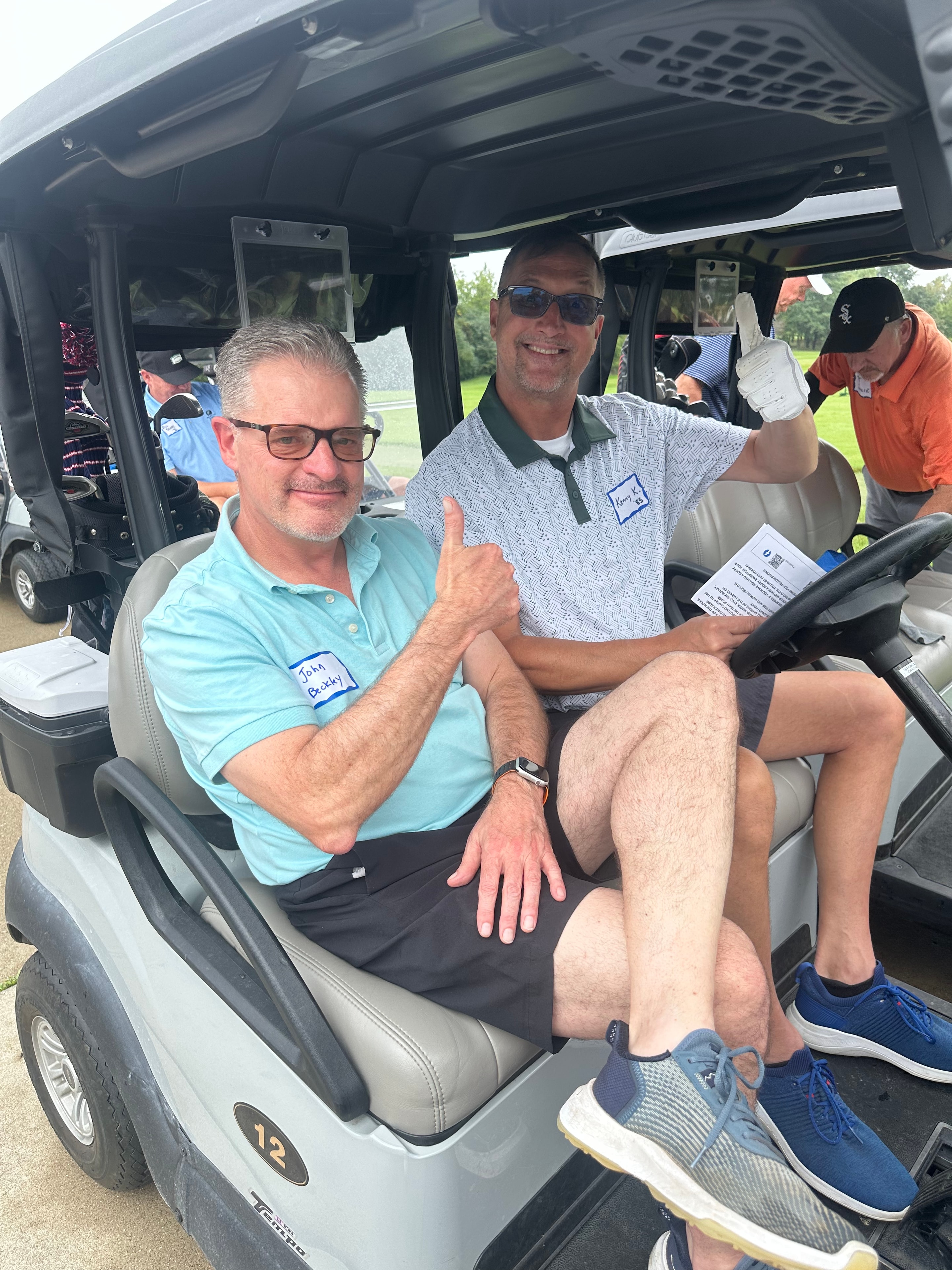 Men in golf cart giving thumbs up