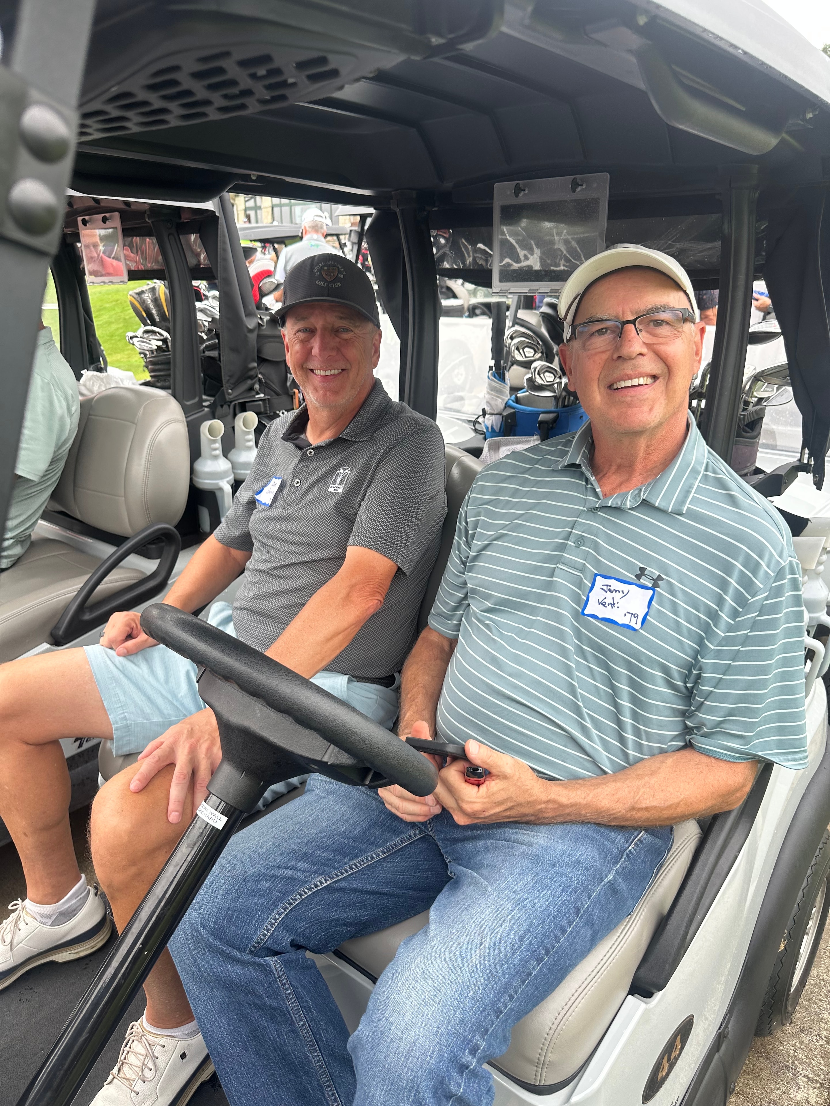 Two men smiling inside golf cart