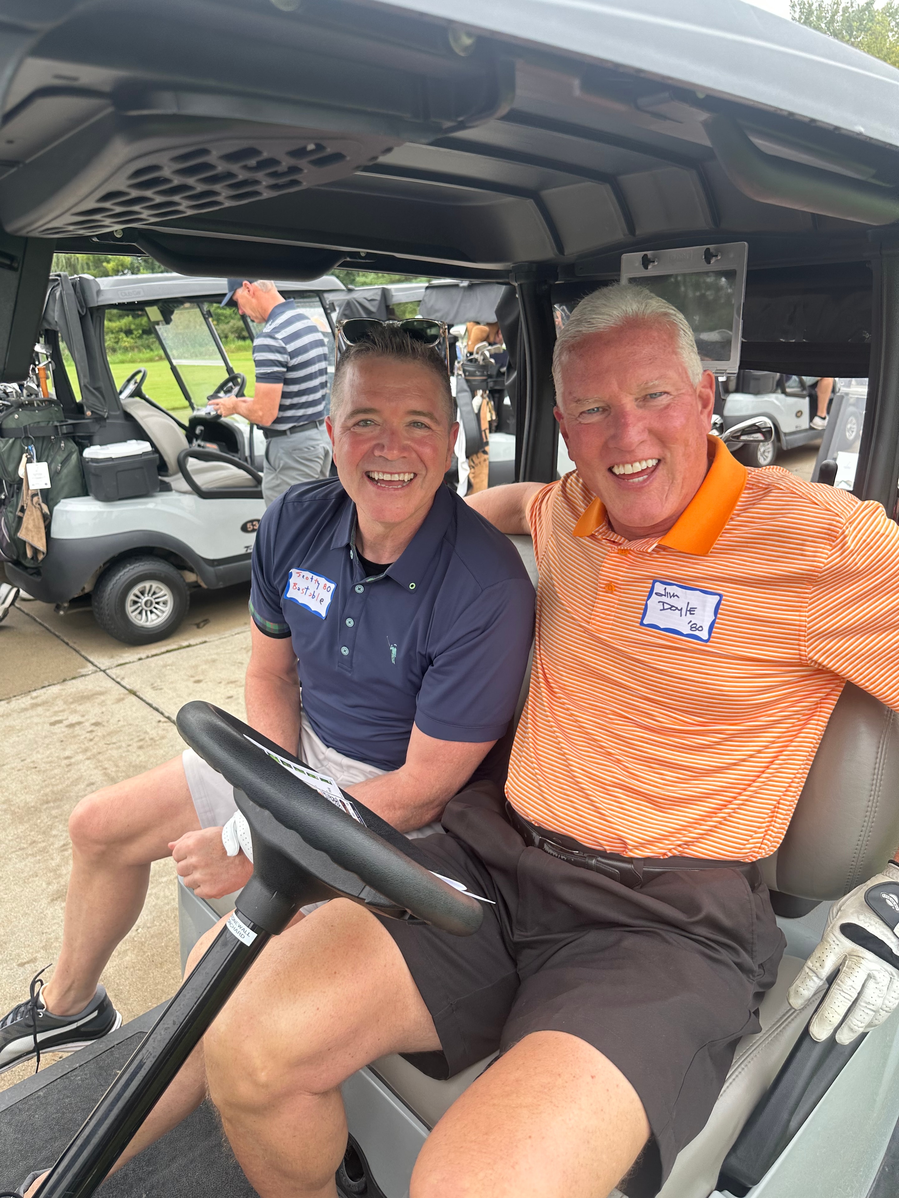 Two men smiling in golf cart