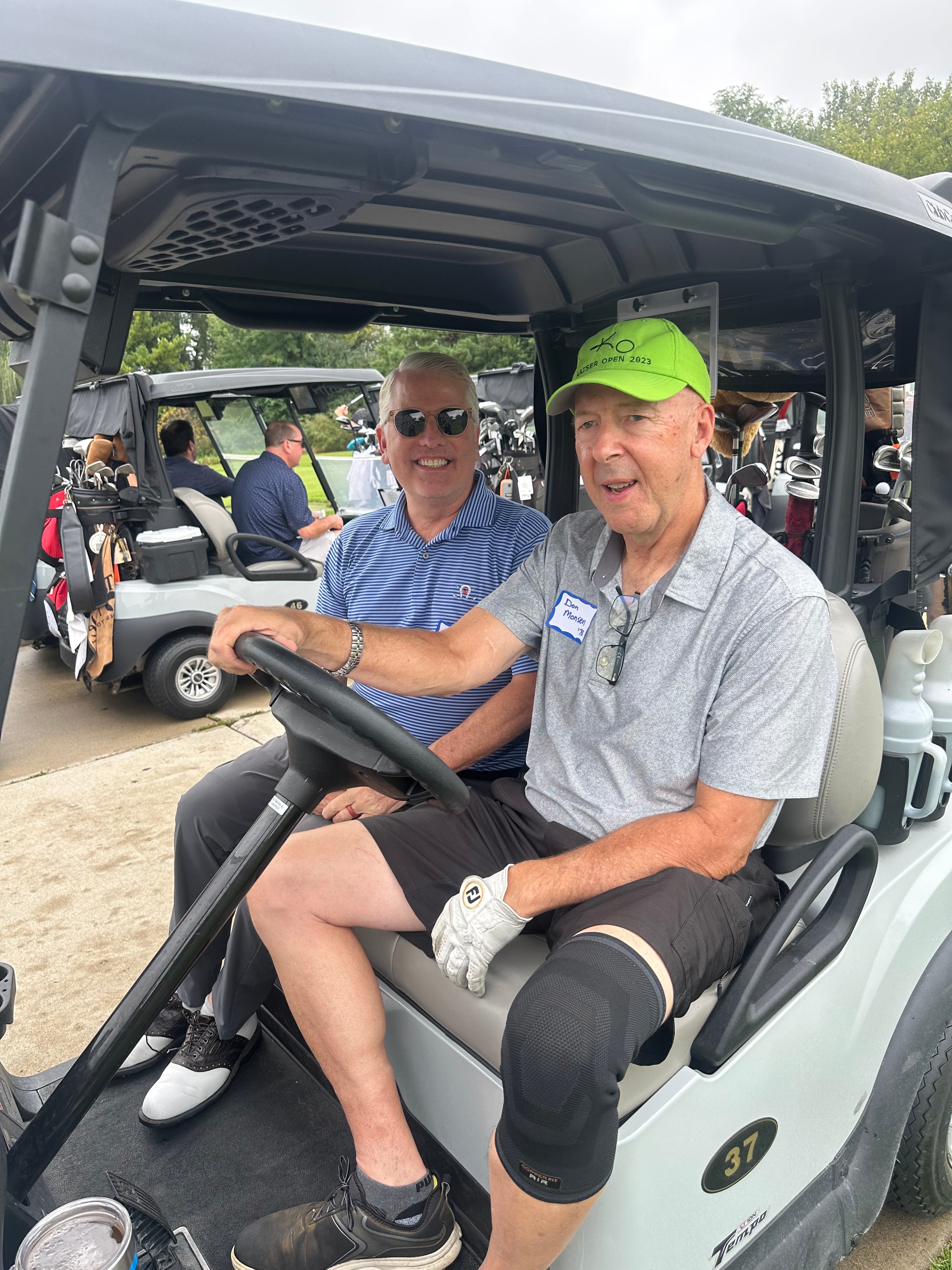 Two men smiling in golf cart