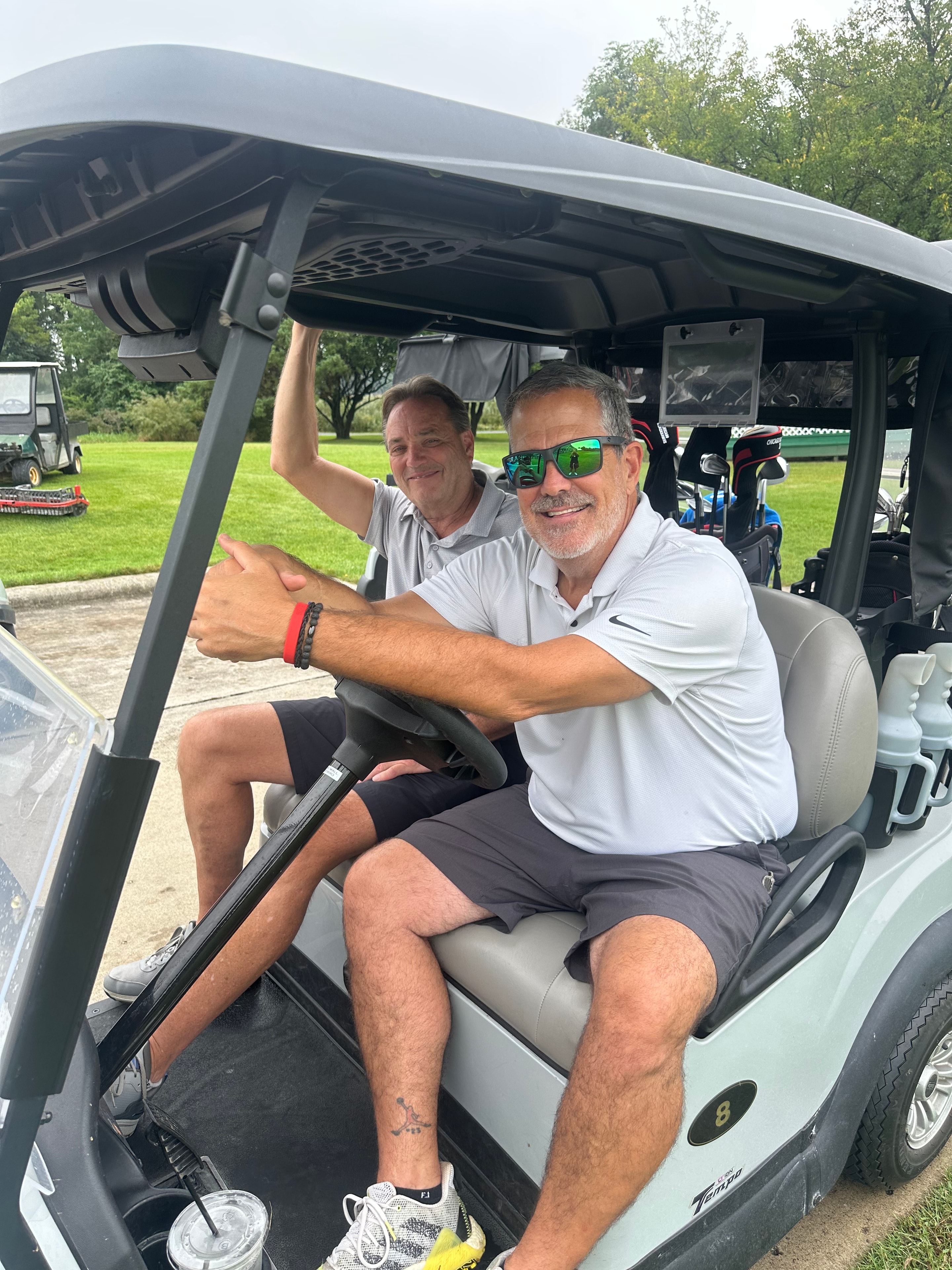 Two men smiling in golf cart