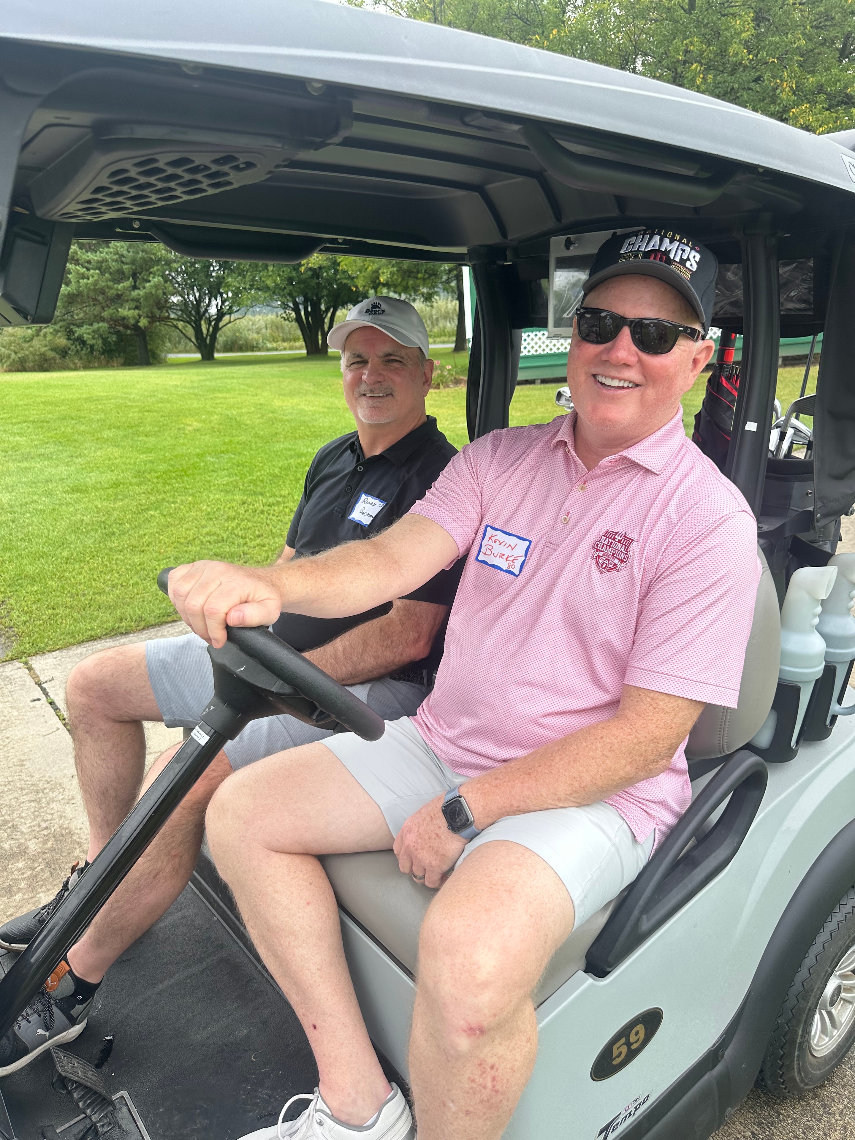 Two men smiling in golf cart