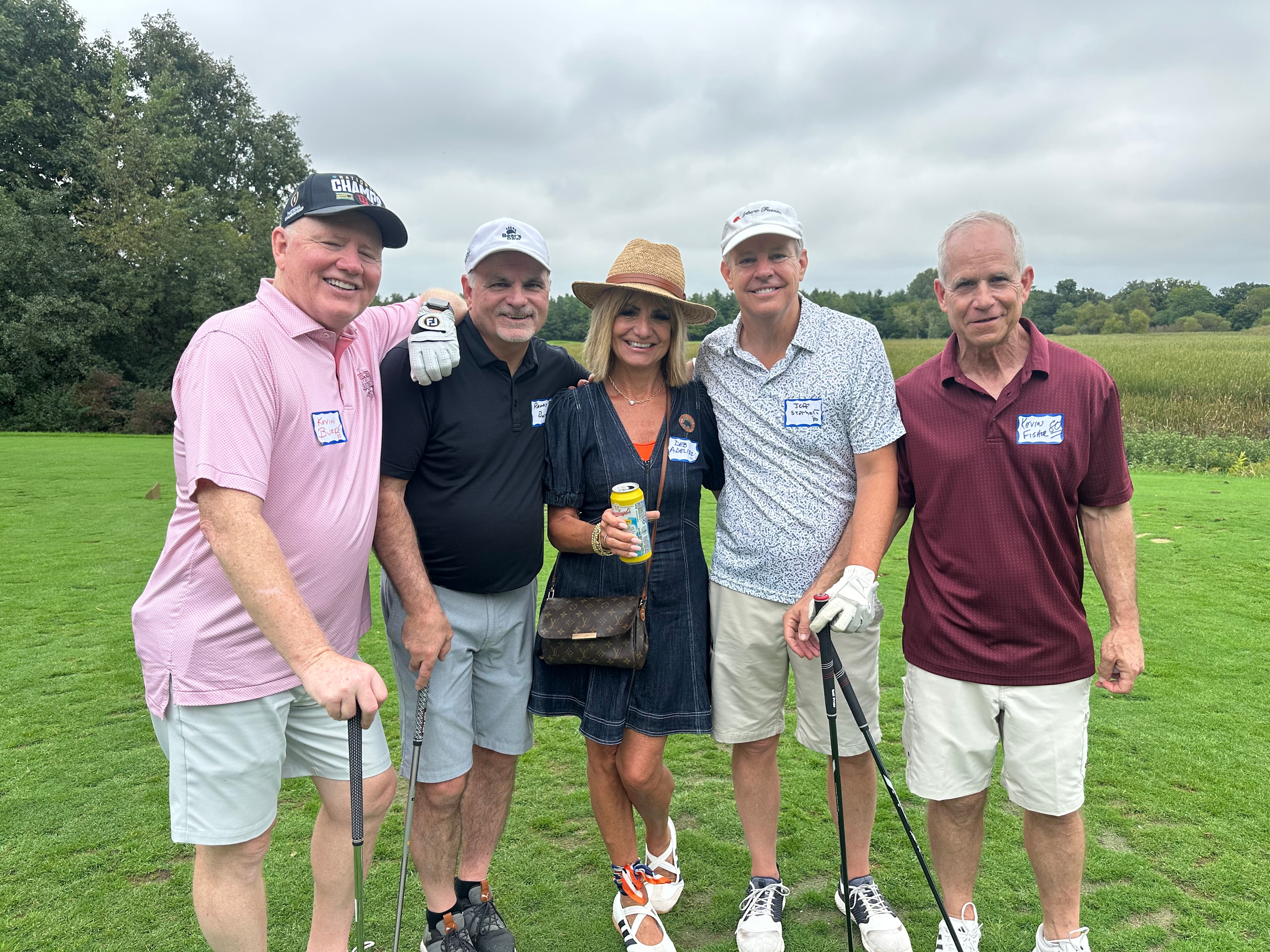 Five golfers posing on green course