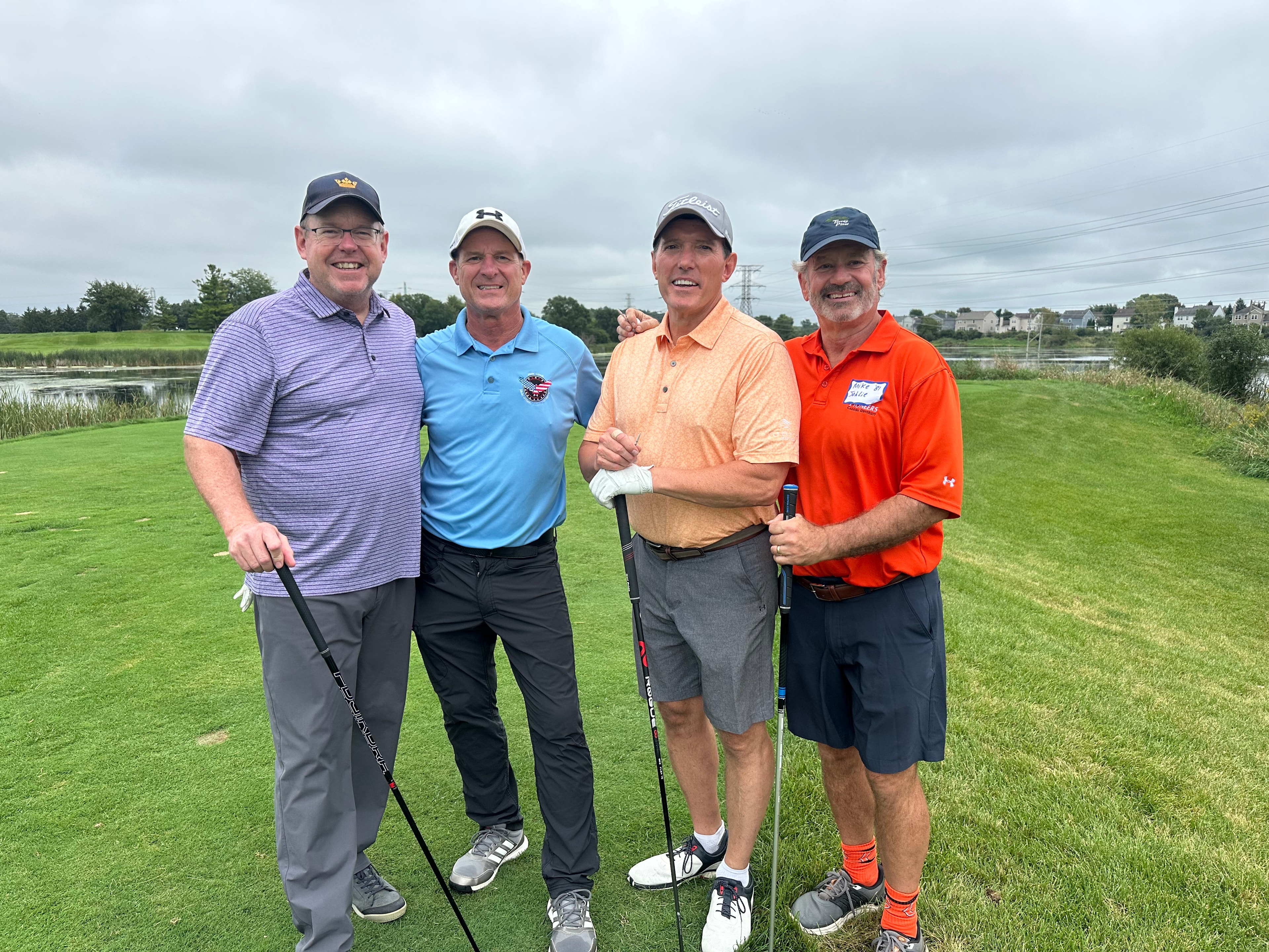 Four men posing on golf course waterfront