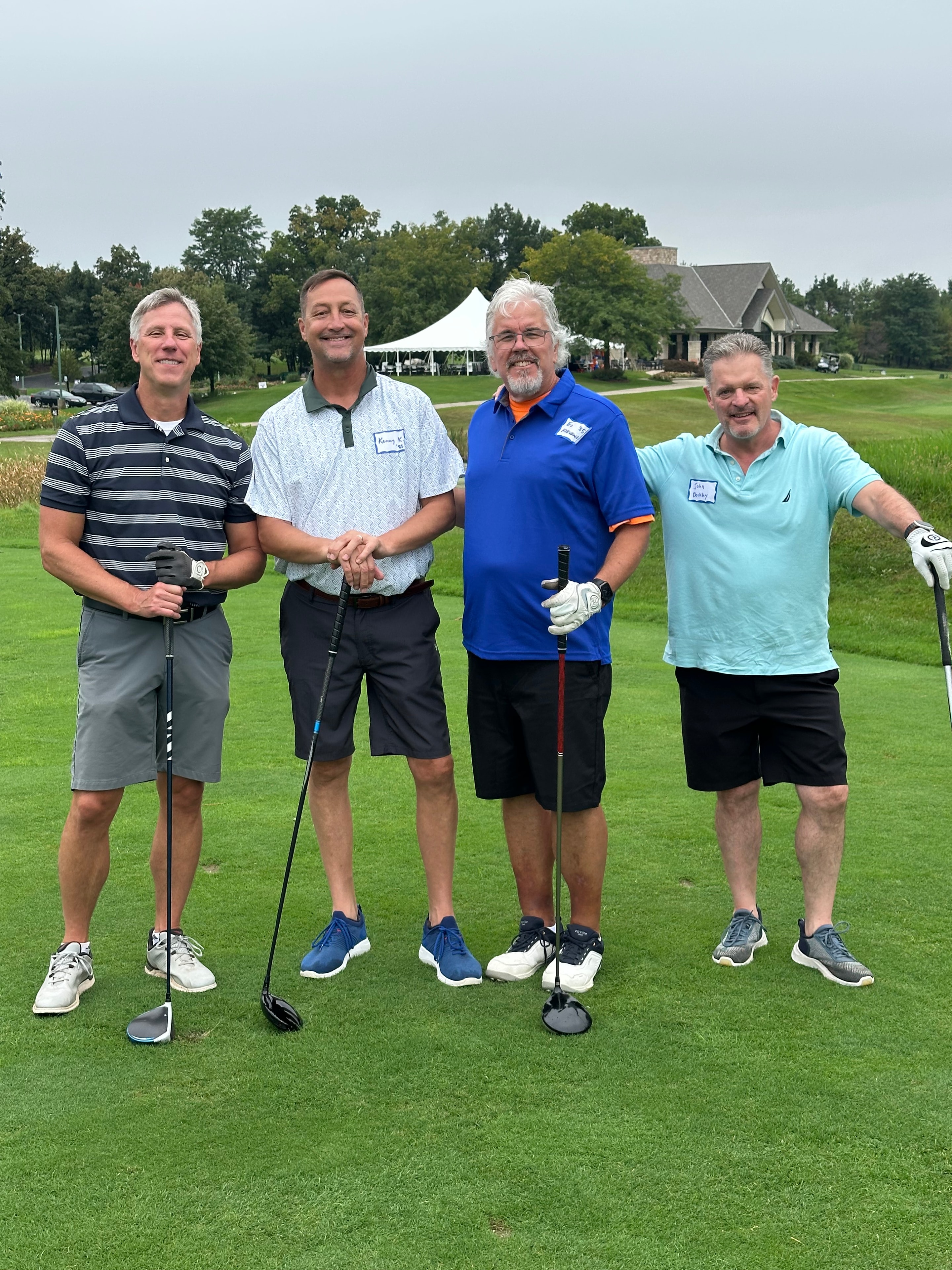 Four men posing at golf course outing