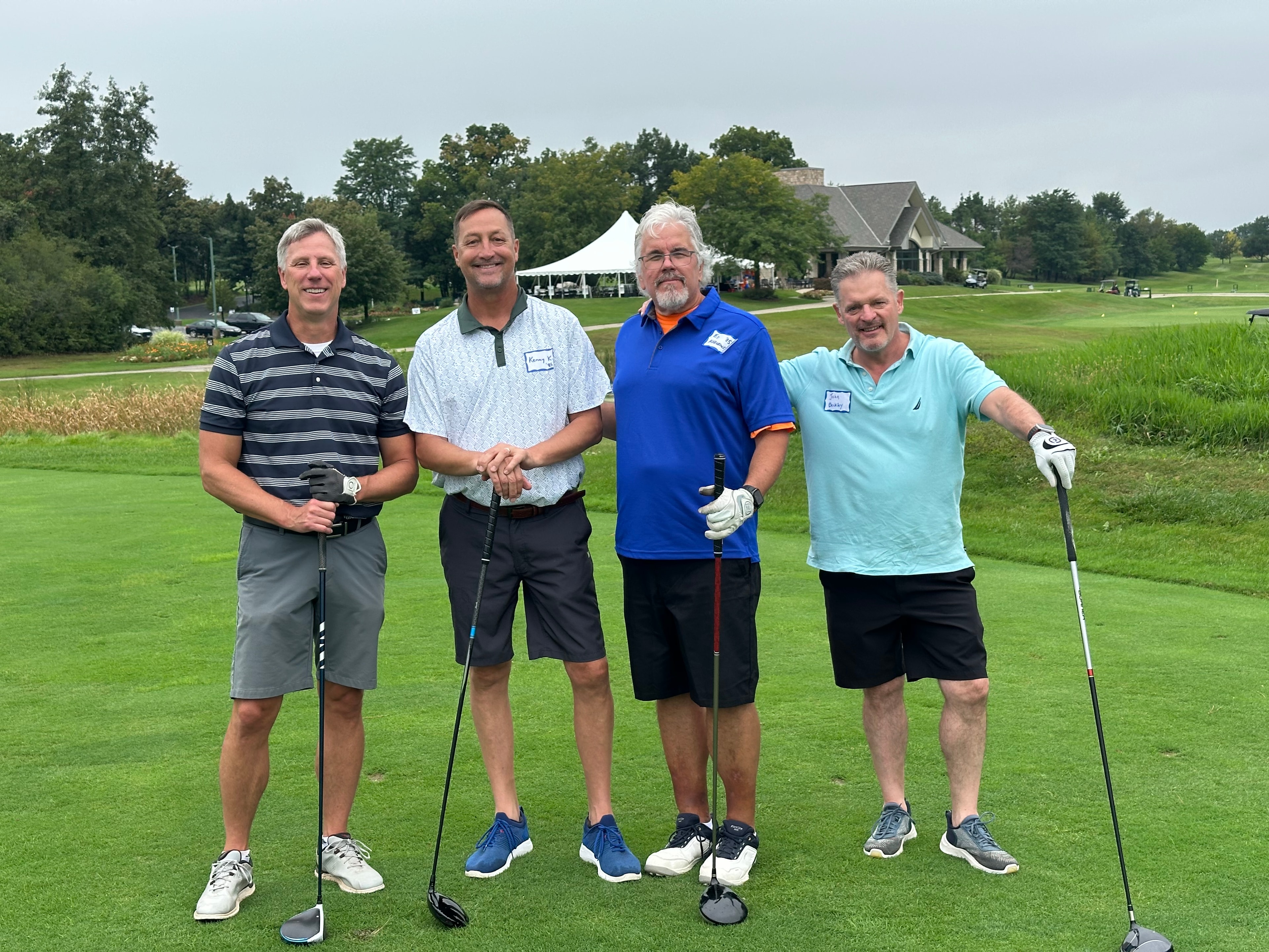 Four men posing at golf course event
