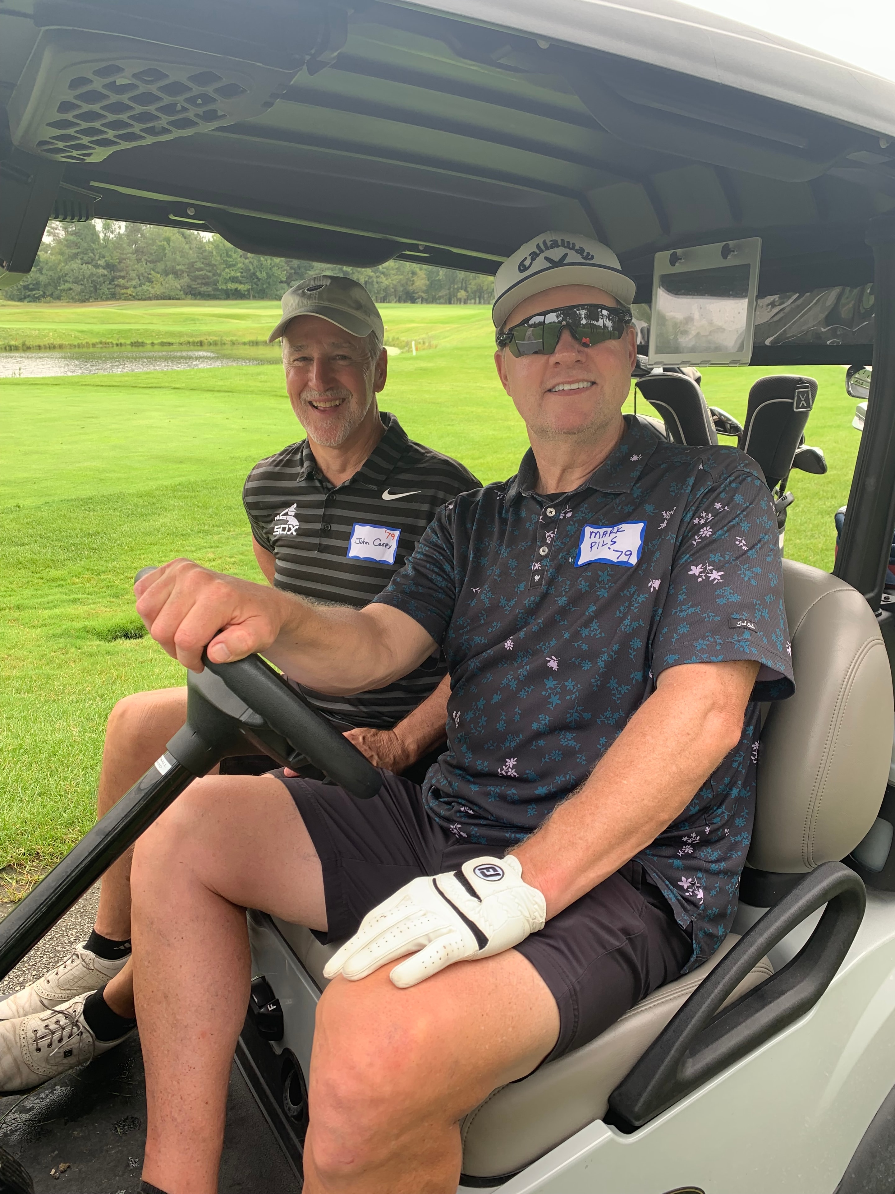 Two men smiling in golf cart