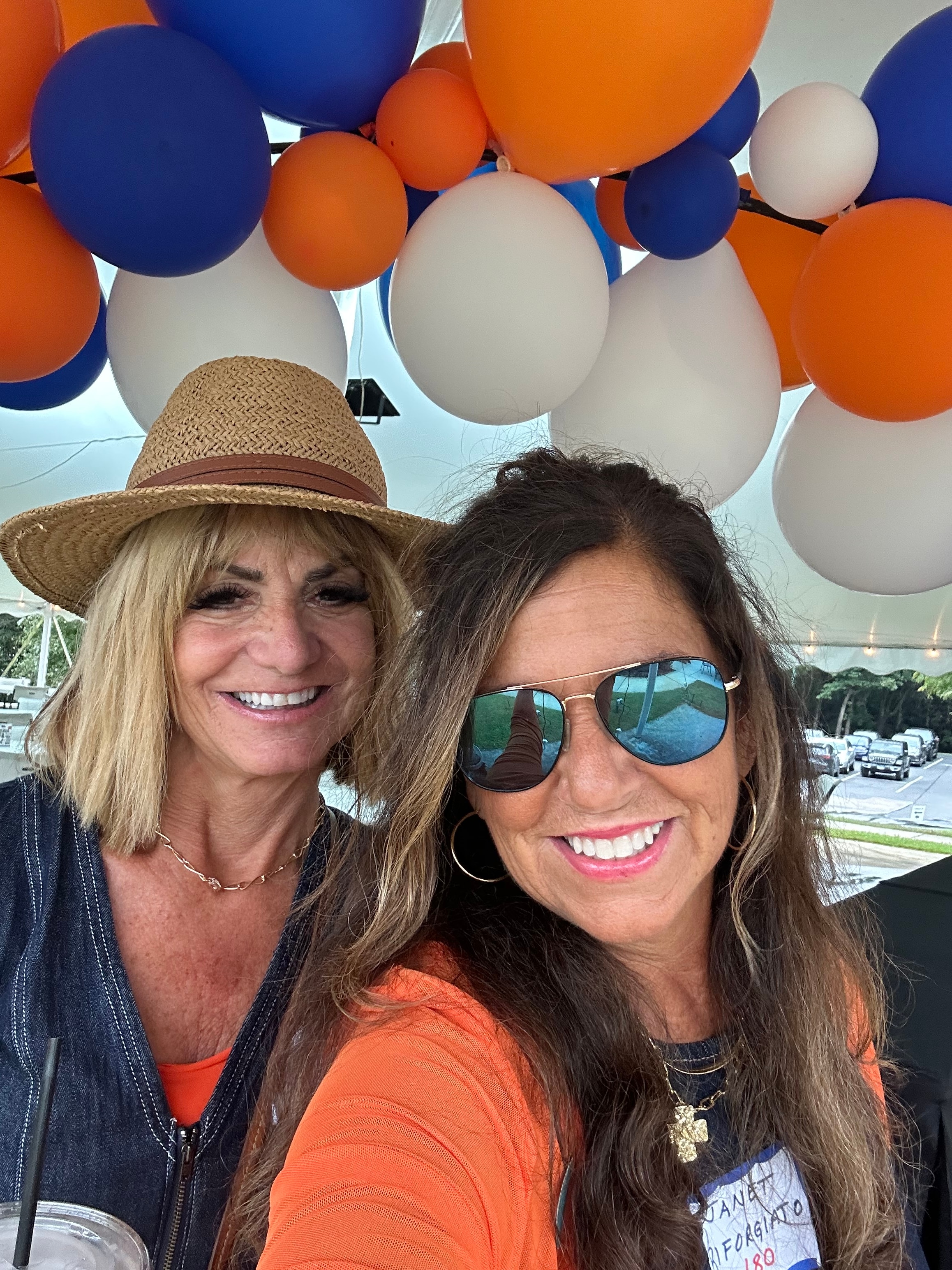 Two women smiling under colorful balloons