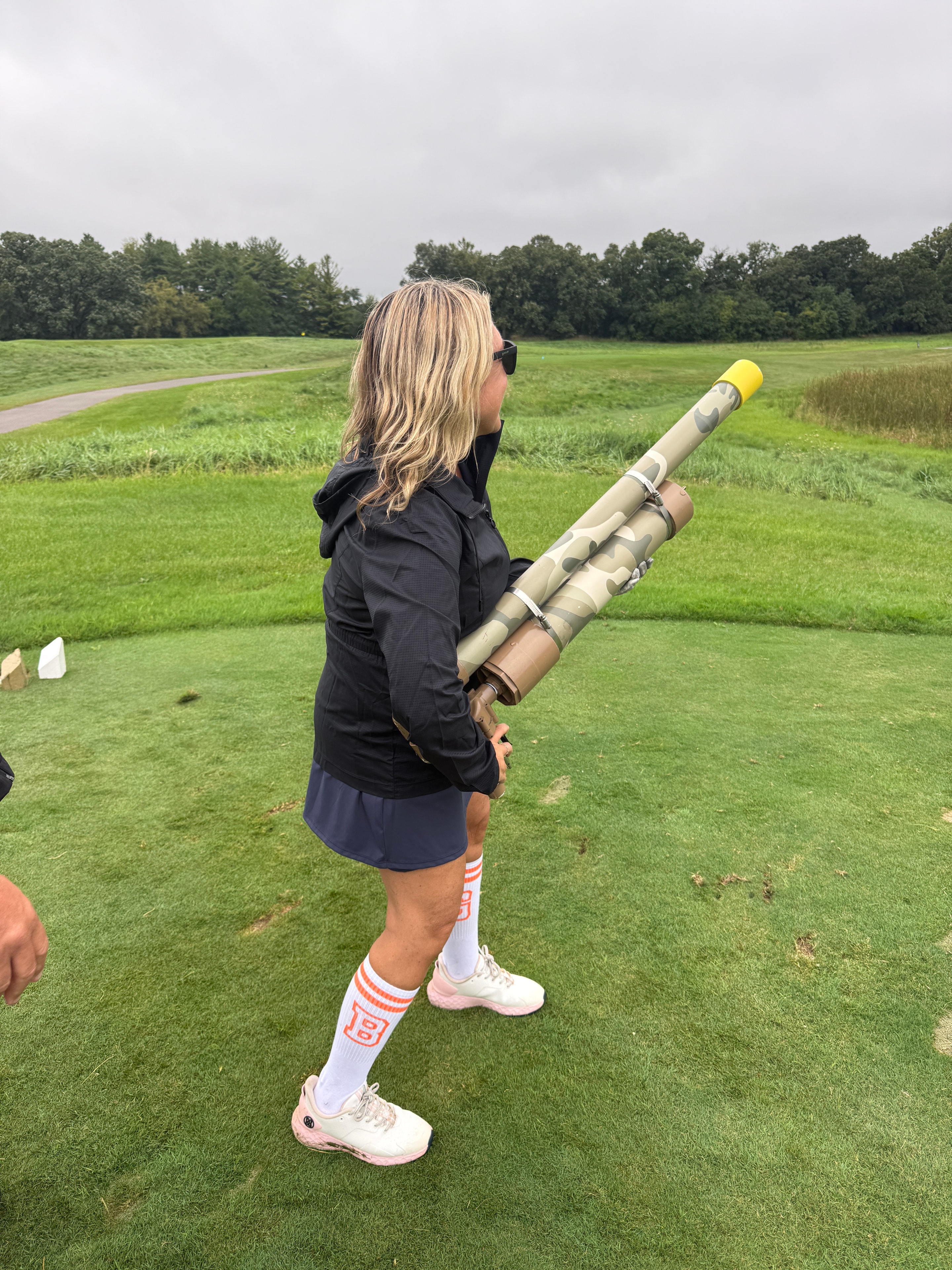Woman holding golf ball cannon in field