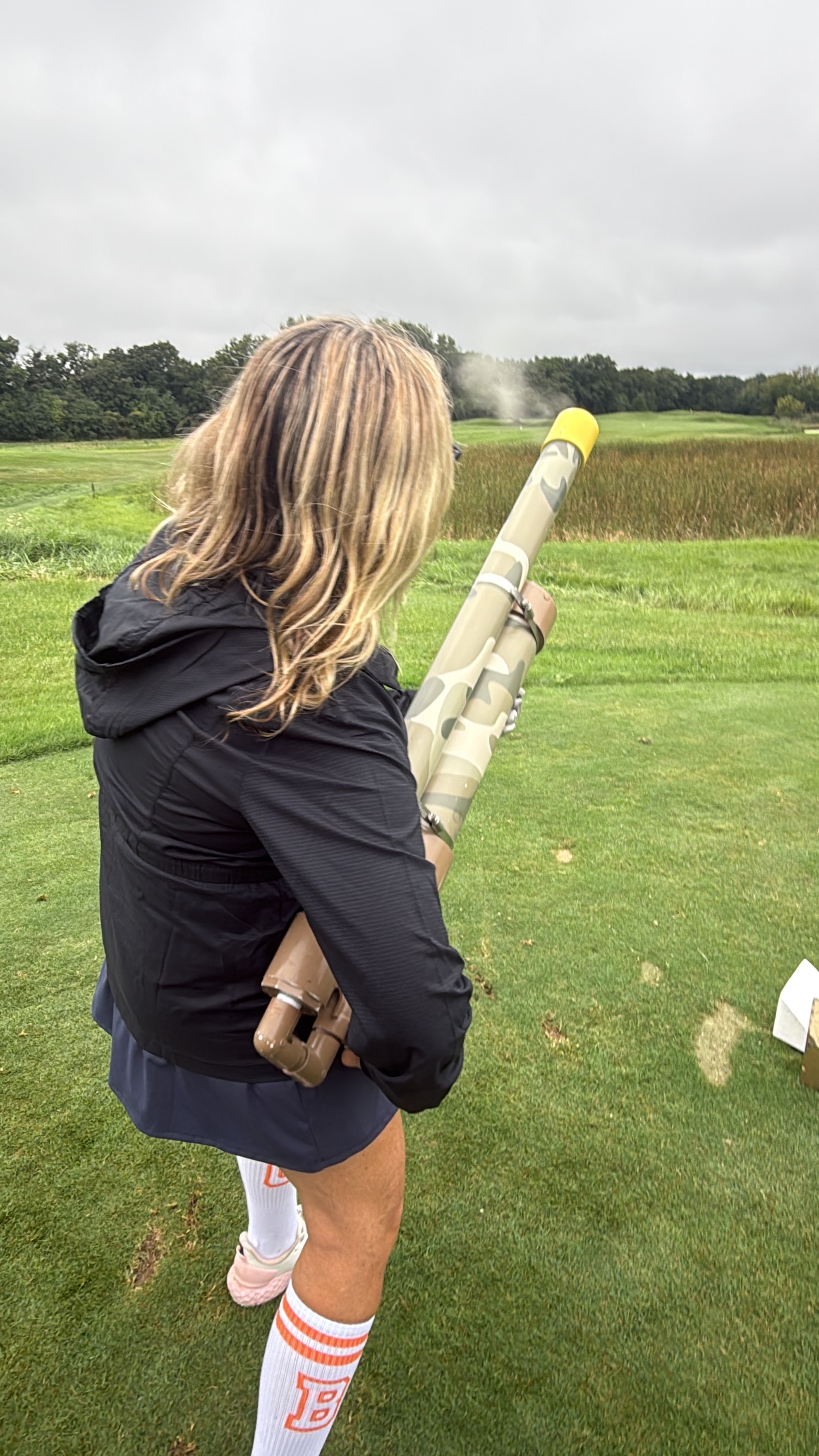 Woman holding golf ball cannon in field