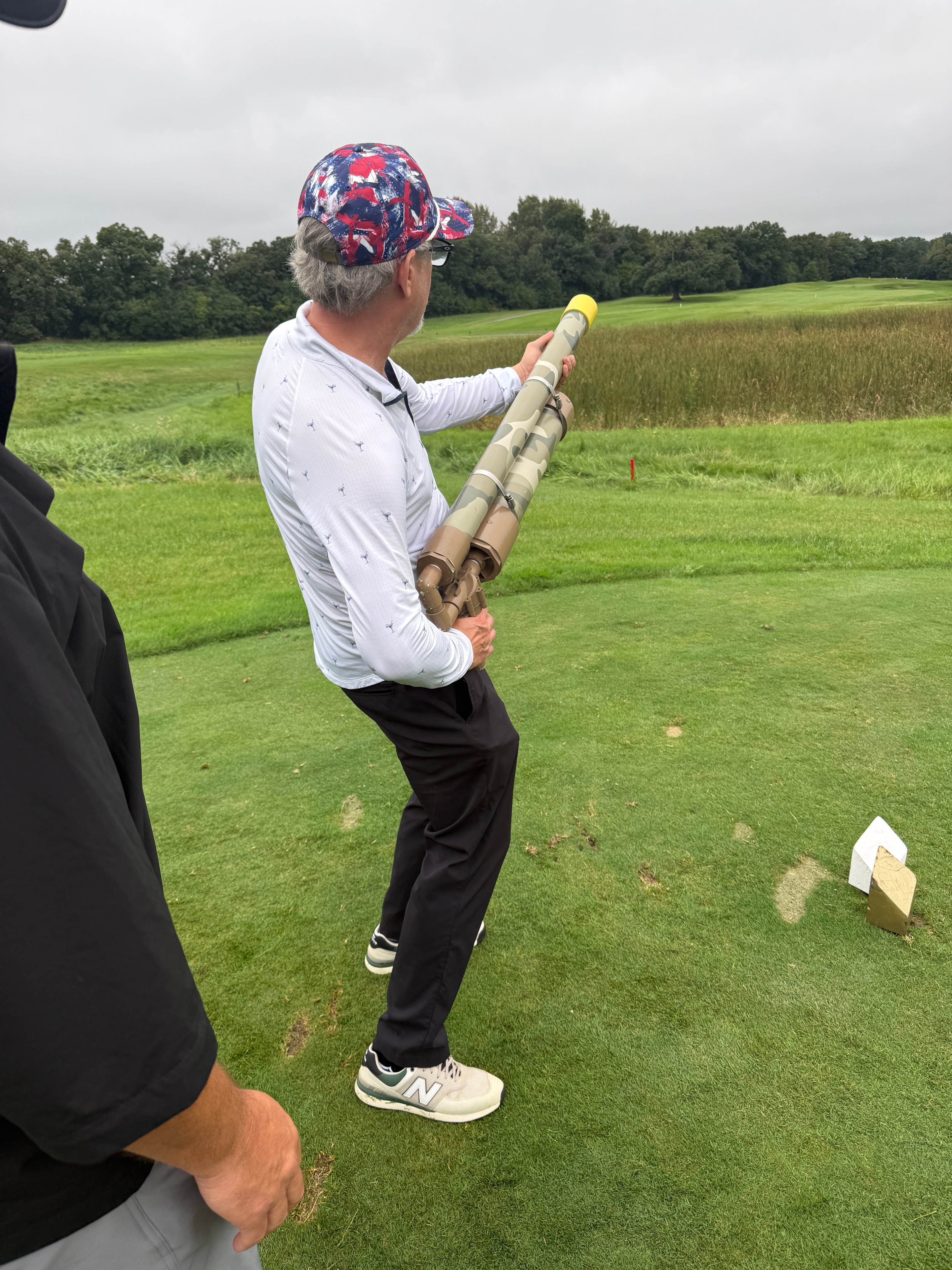 Man holding golf ball cannon in field