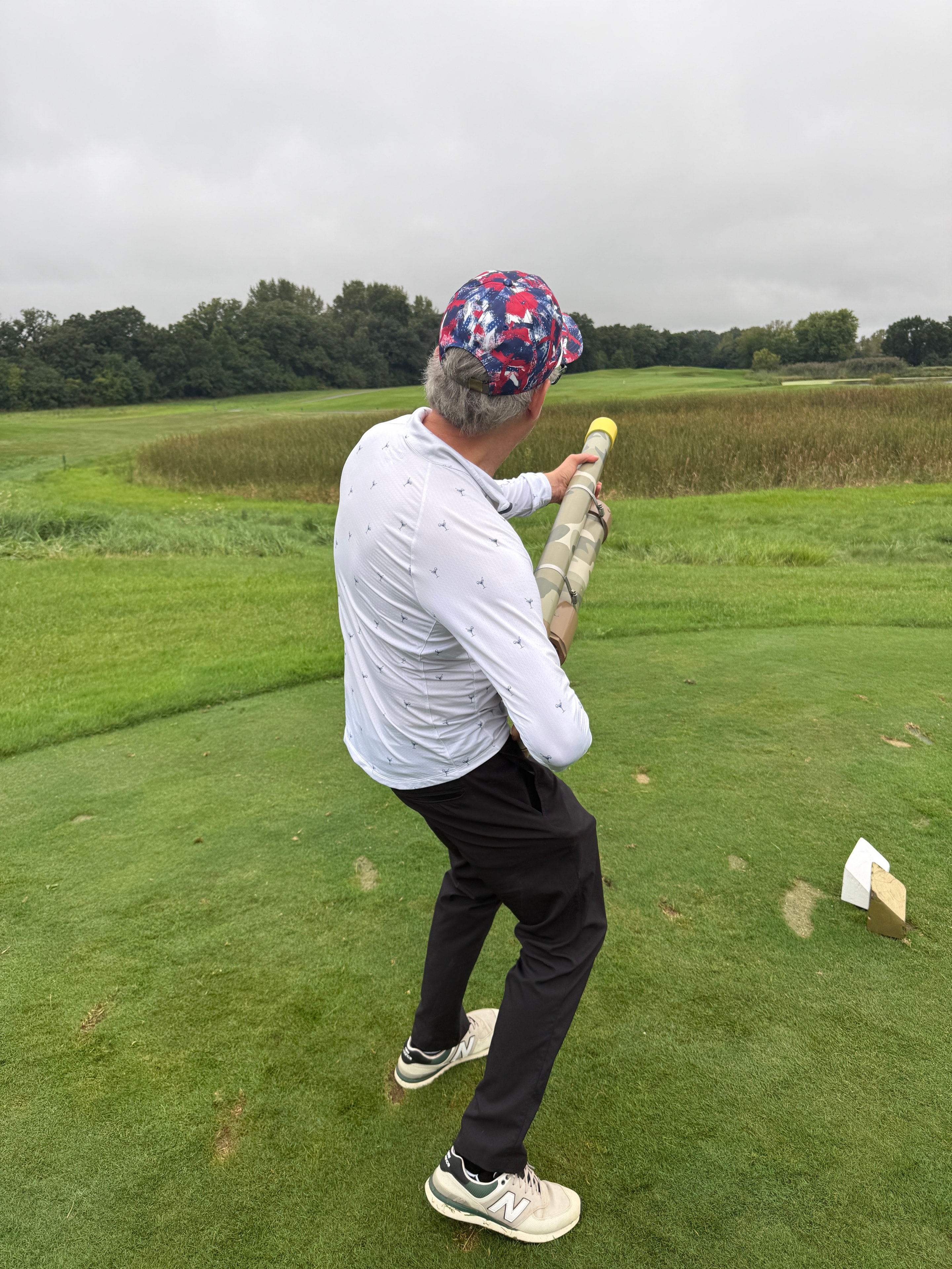 Man holding golf ball cannon in field