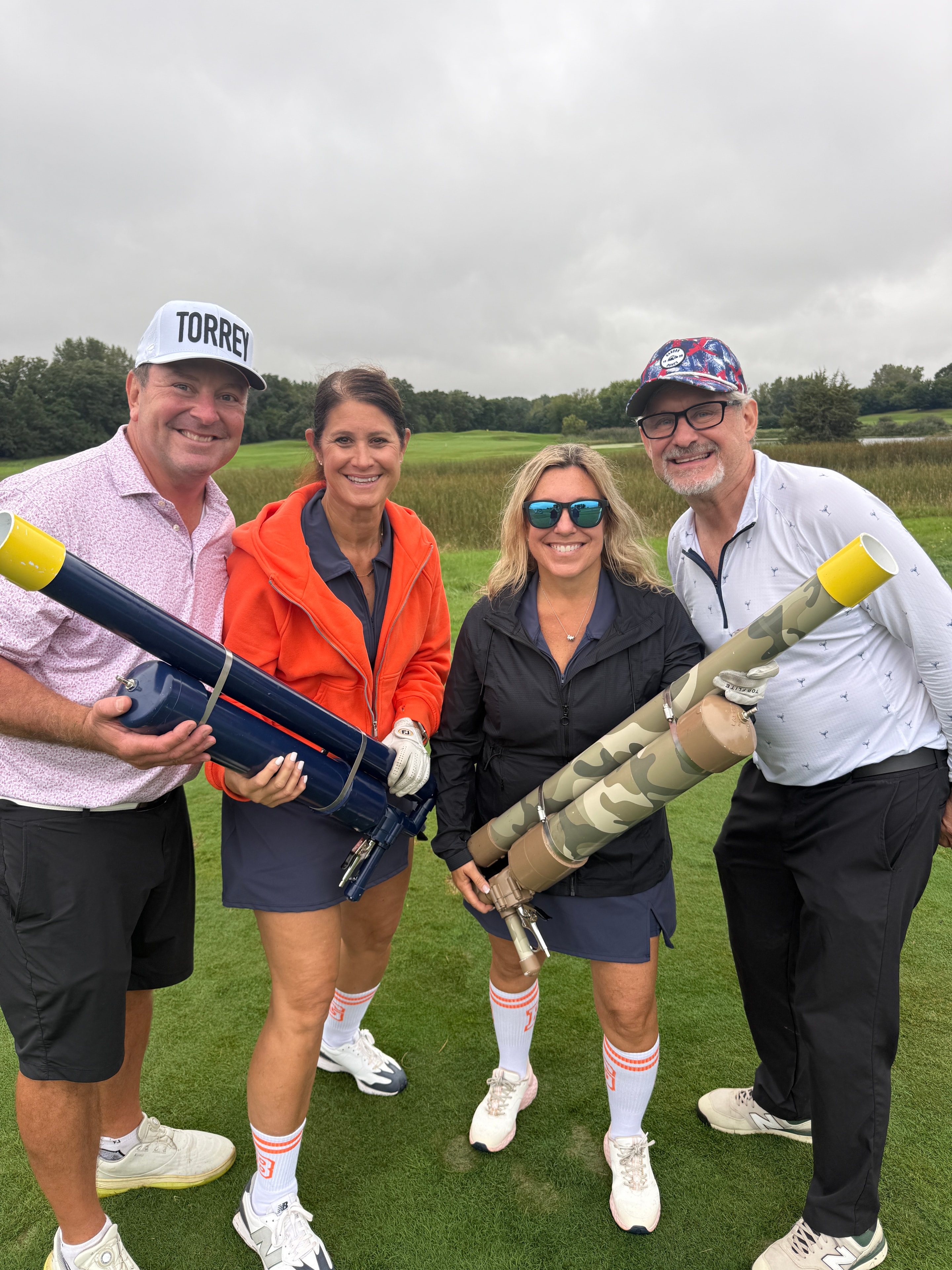 Four people holding golf cannons outdoors