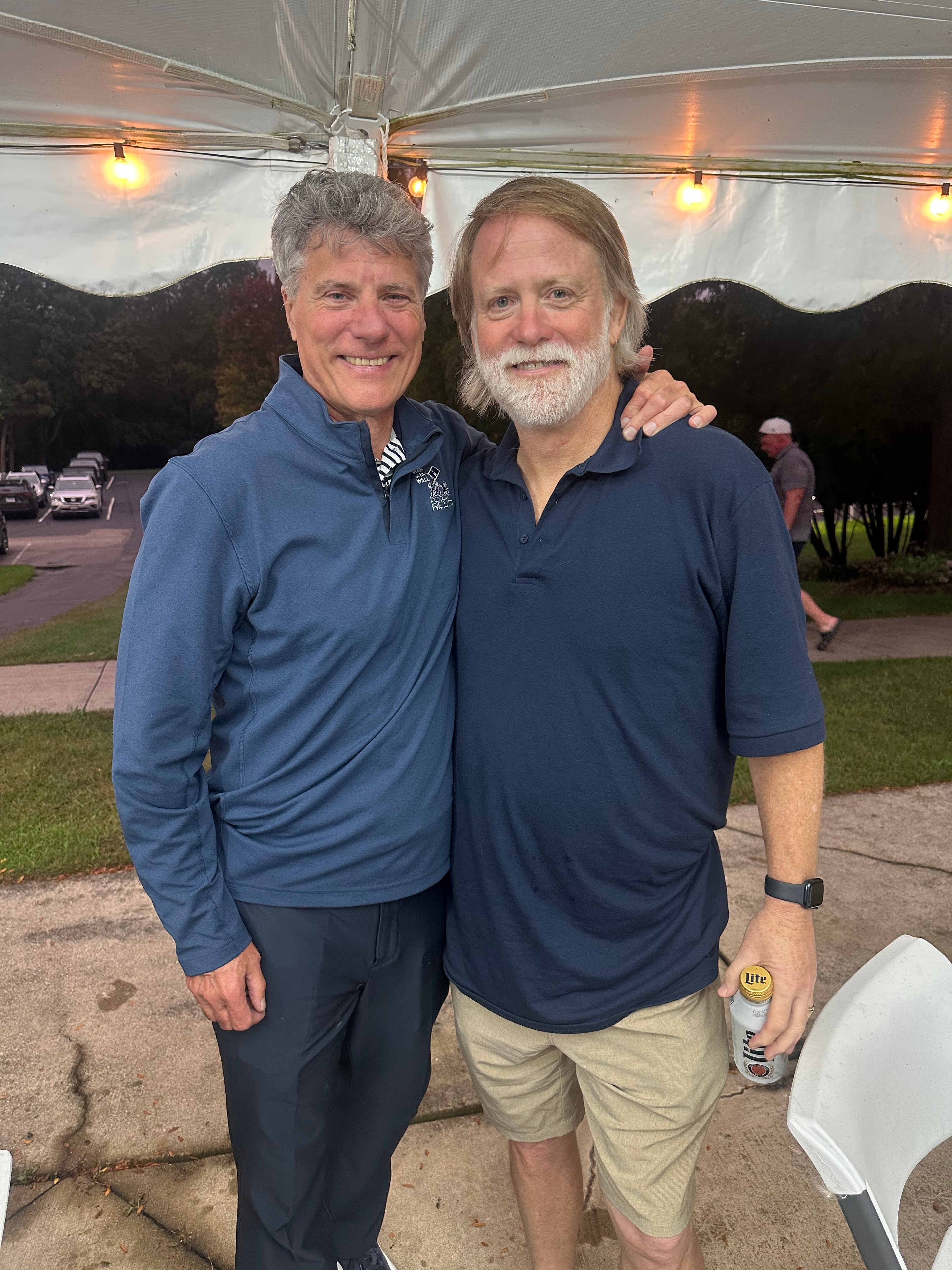 Two men posing under outdoor tent event