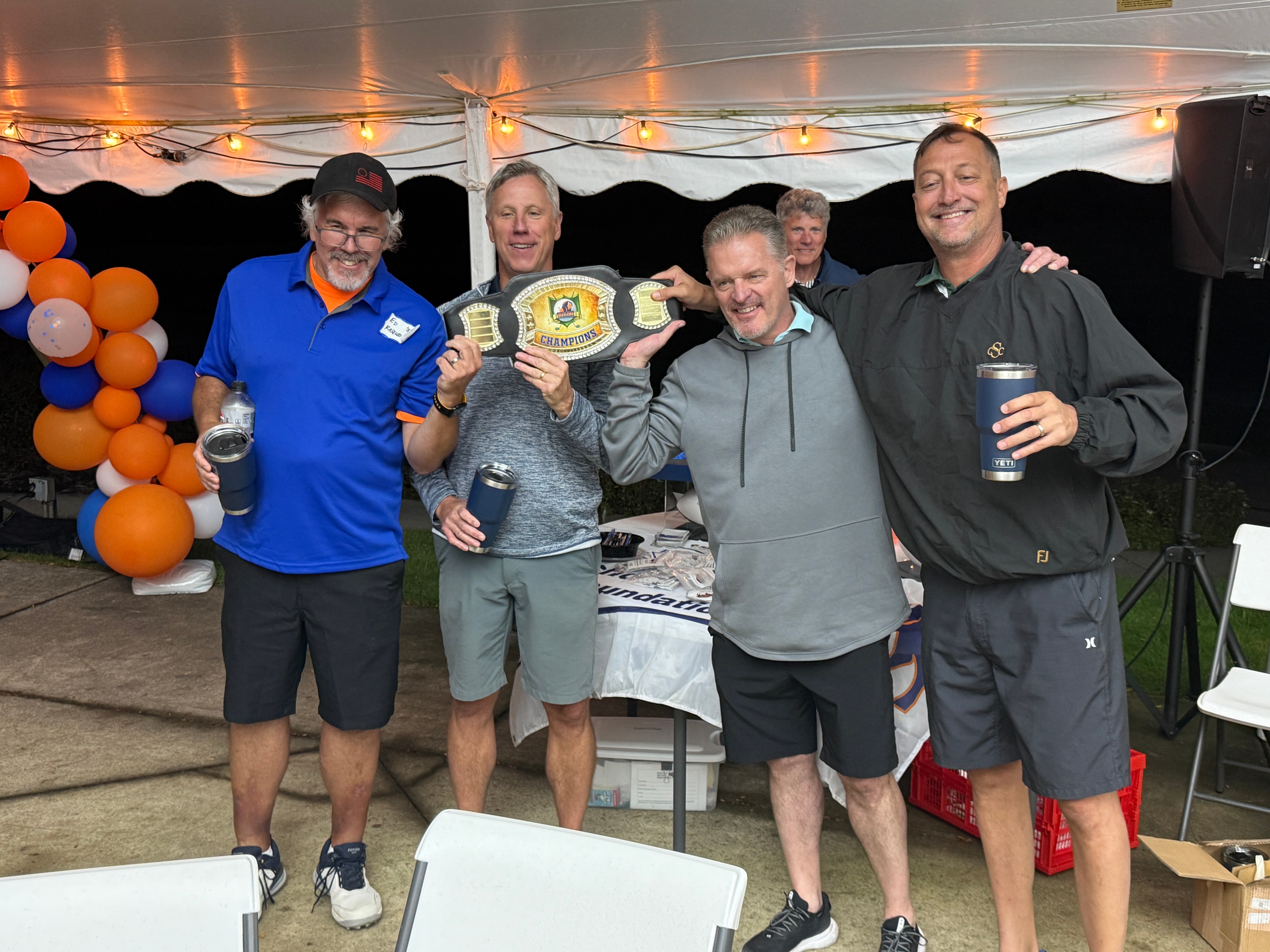 Men celebrating championship belt at event tent