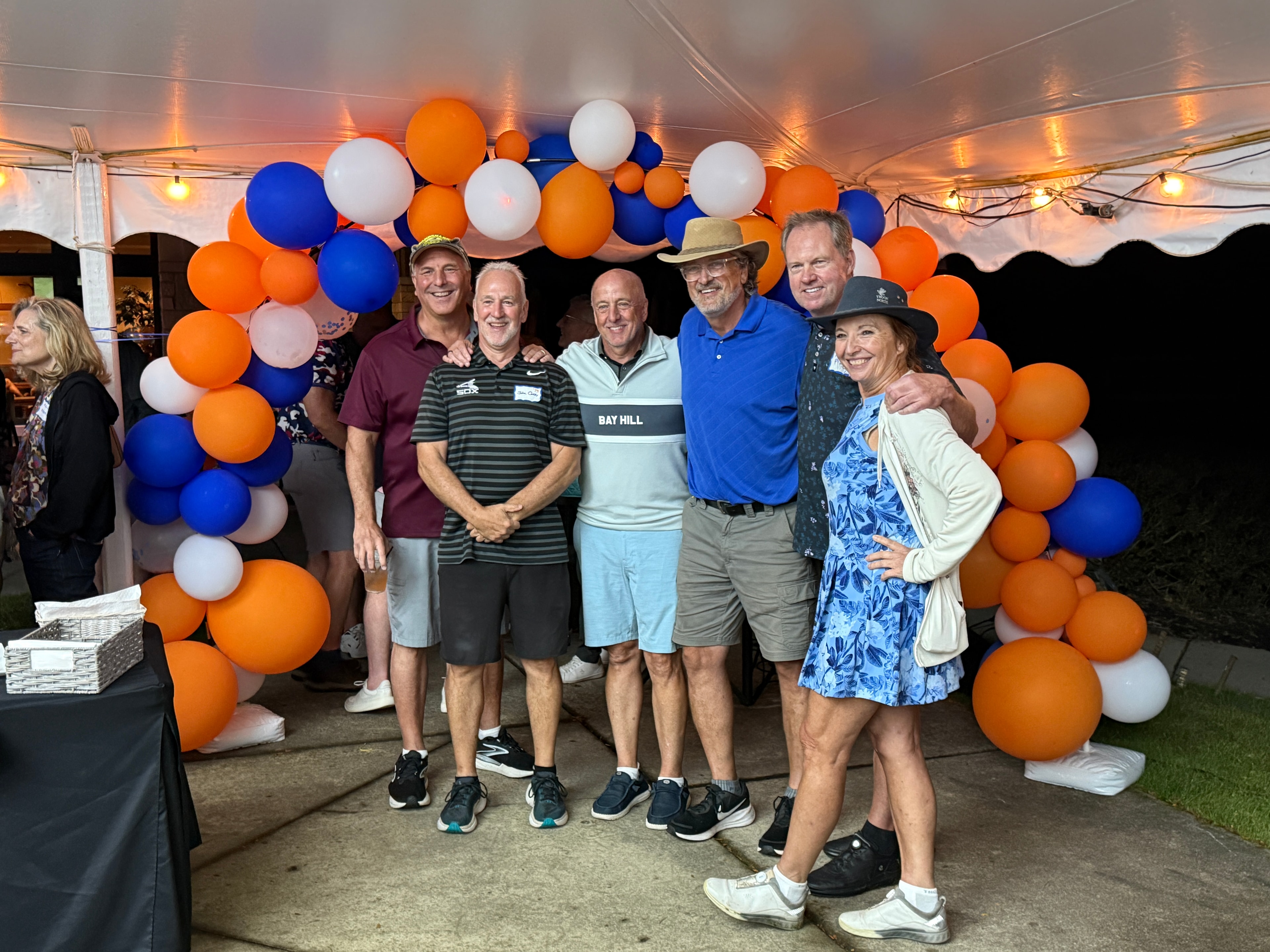 Group posing under blue and orange balloon arch