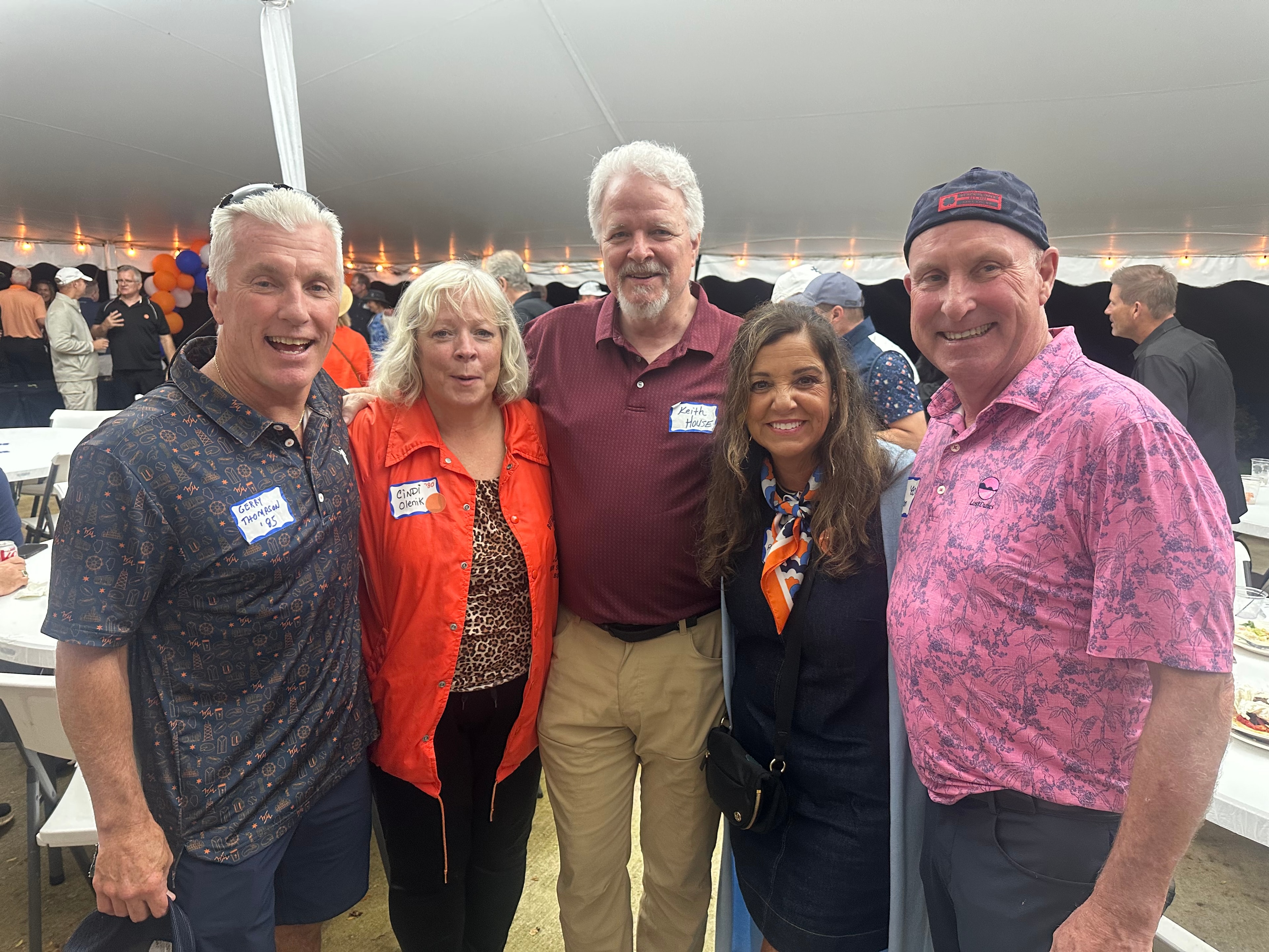 Five people smiling at outdoor event tent