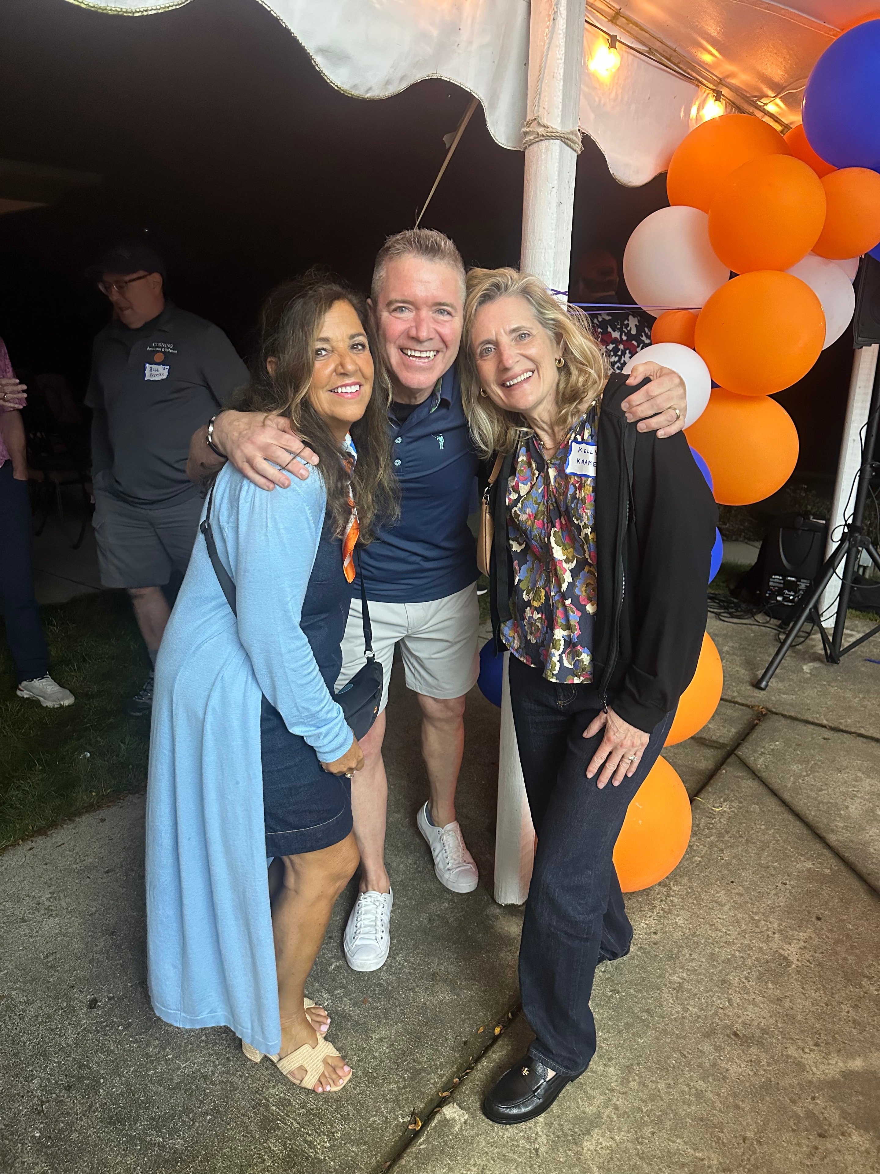Three people posing at outdoor party event