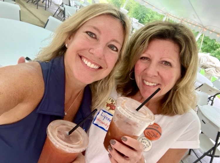 Two women smiling holding drinks outdoors