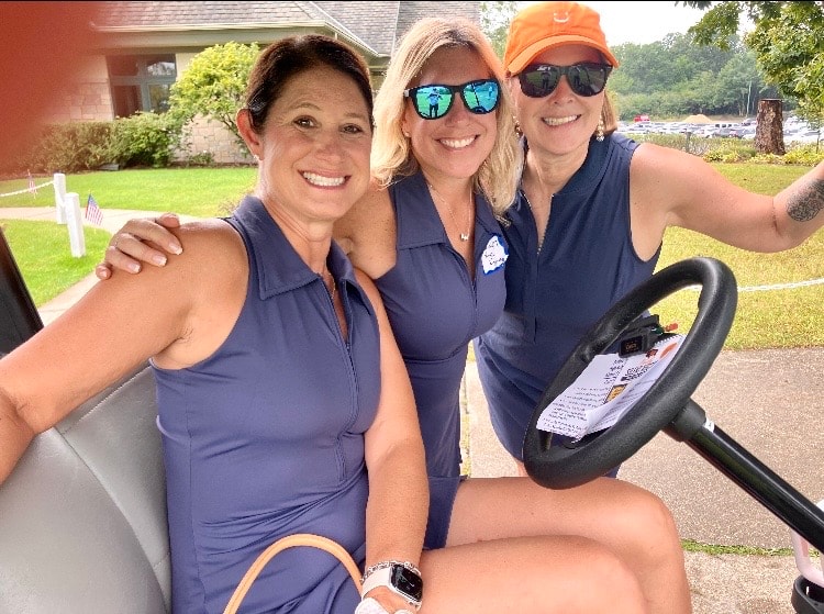 Three women golfing together smiling outdoors