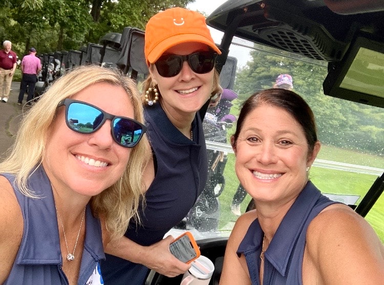 Three women smiling in golf cart