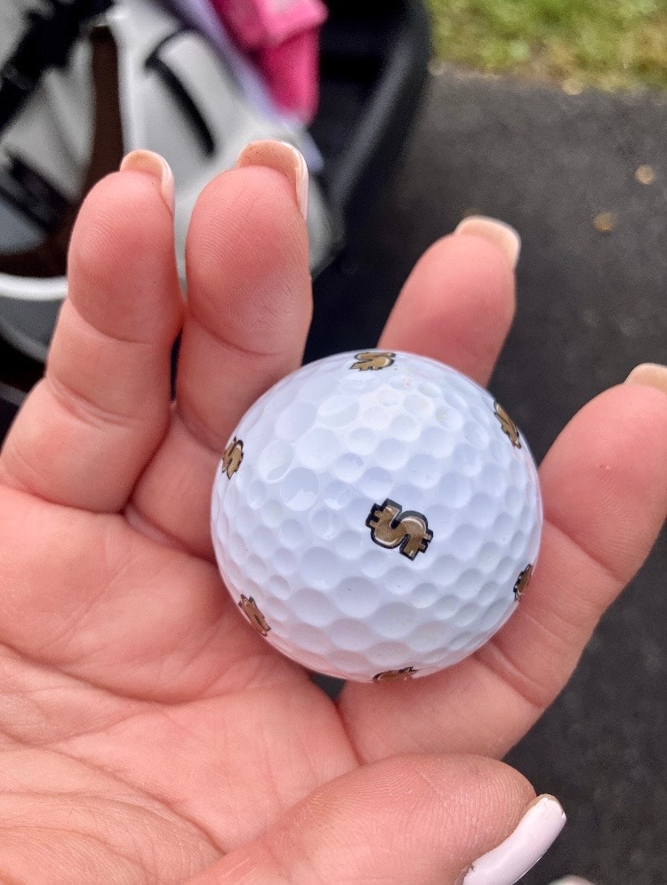 Hand holding white golf ball outdoors
