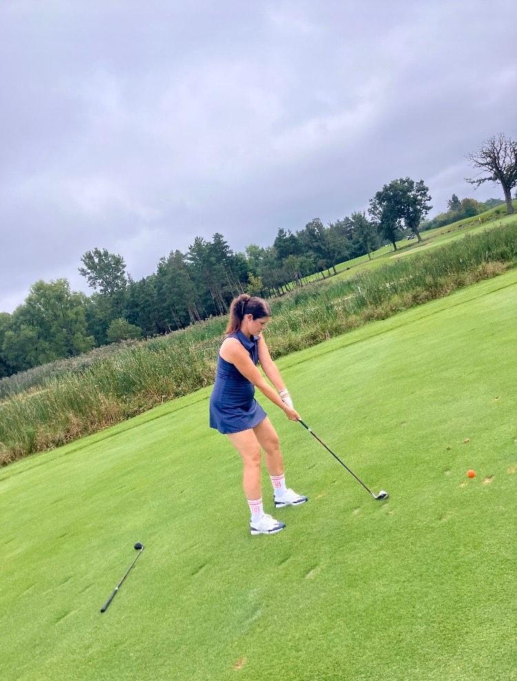 Woman golfing on green hillside course
