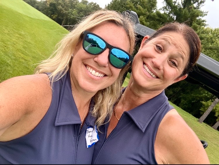 Two women smiling outdoors on sunny day