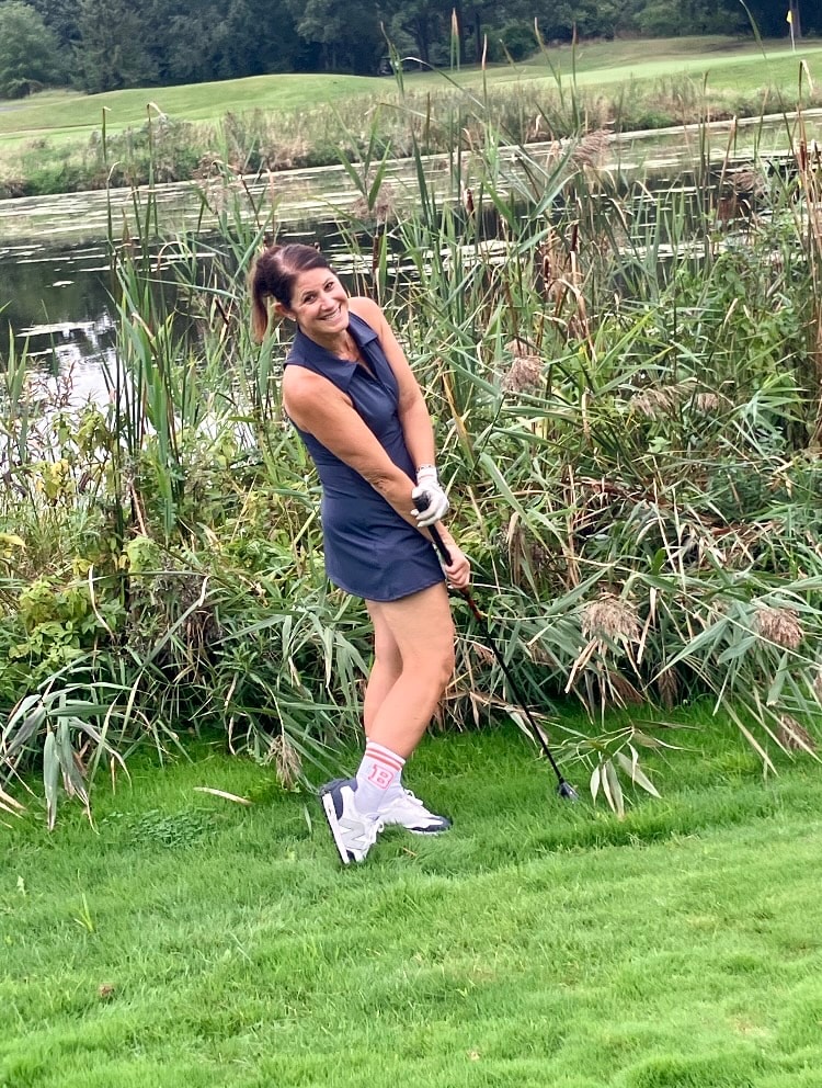 Woman golfing by wetland marsh